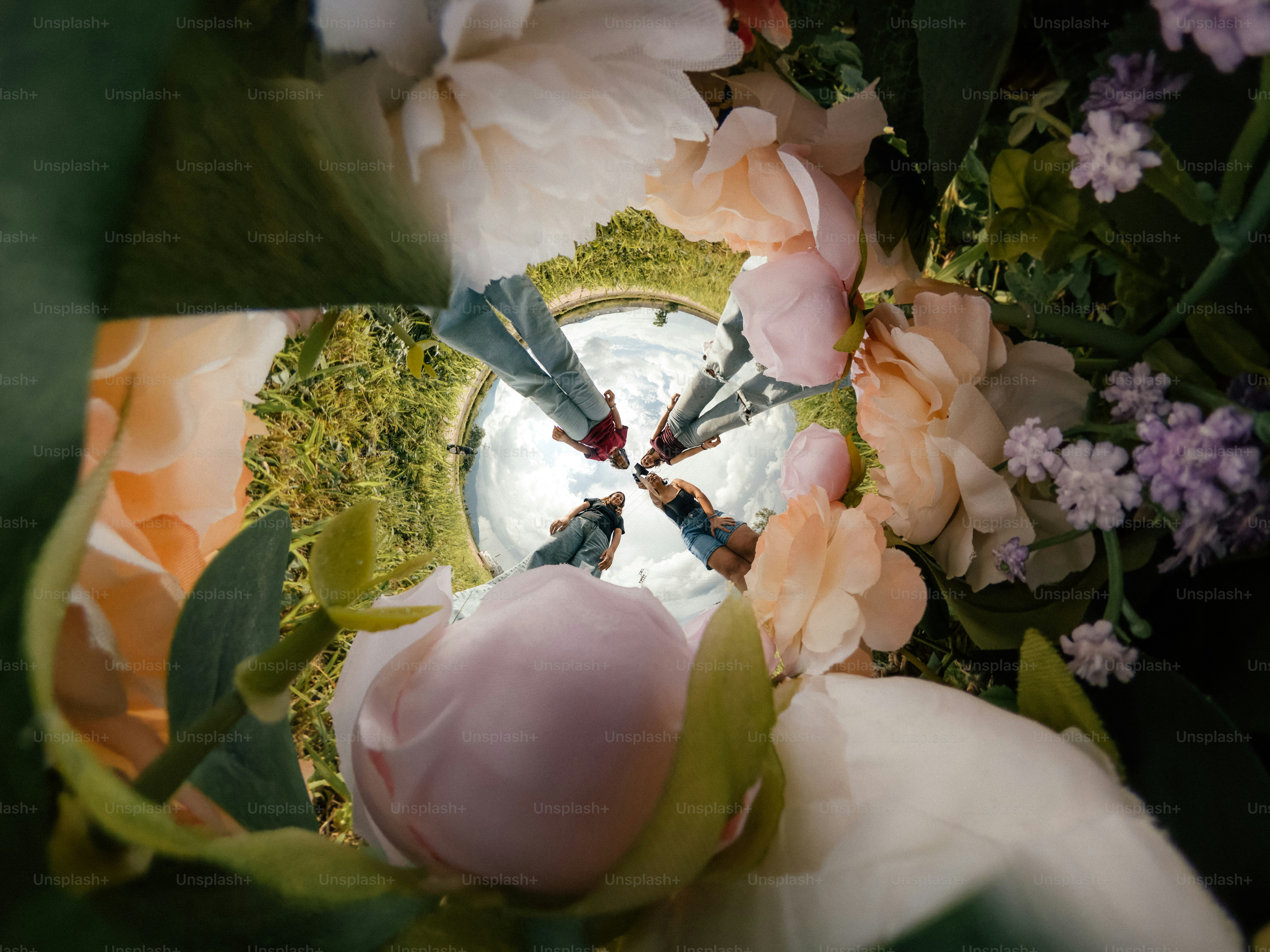 A group of people seen from below through a circular frame of flowers