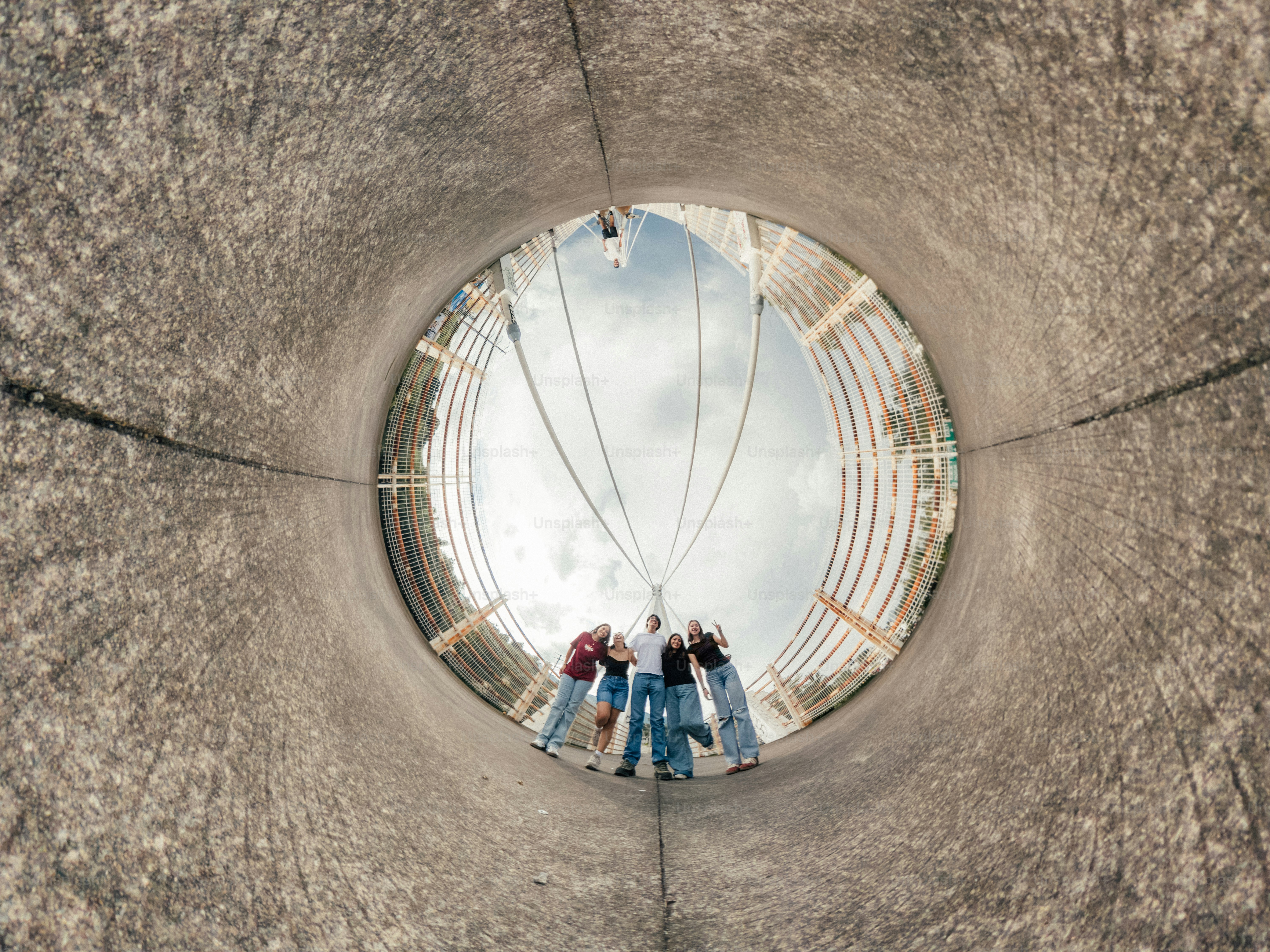 A group of five people standing together on a bridge viewed through a tunnel