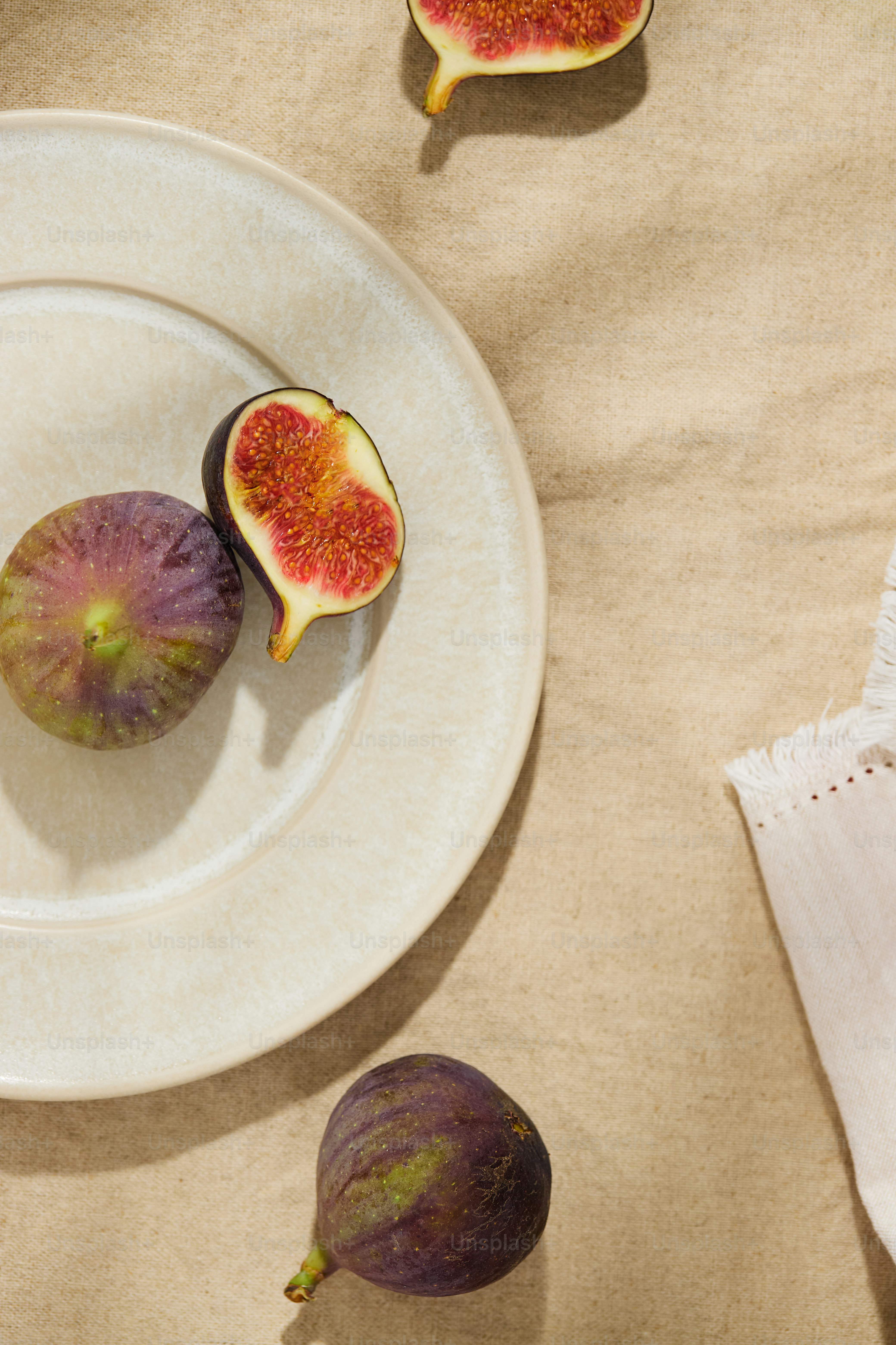Whole and halved figs on a ceramic plate with a linen cloth