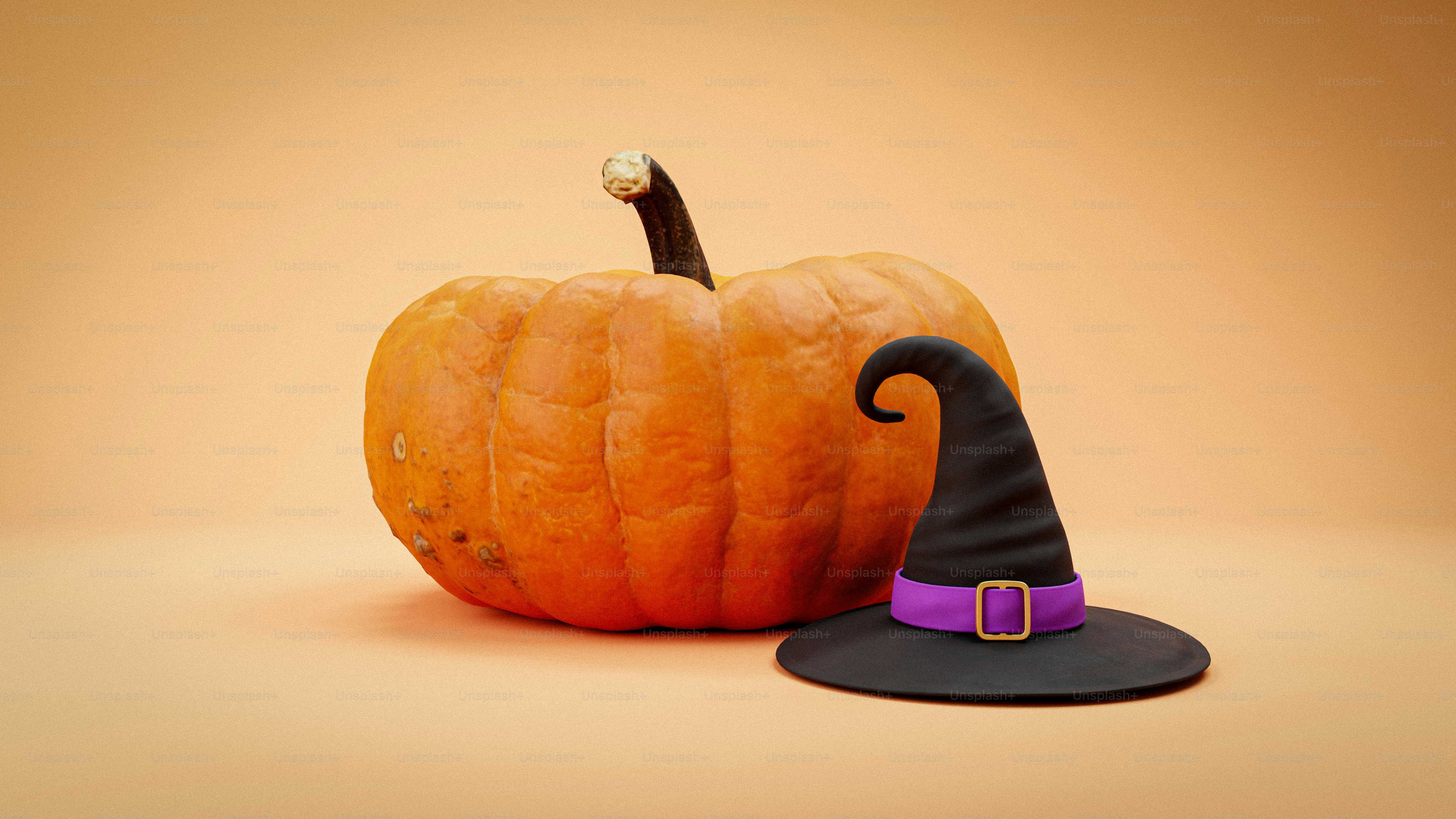 An orange pumpkin beside a black witch hat with a purple band