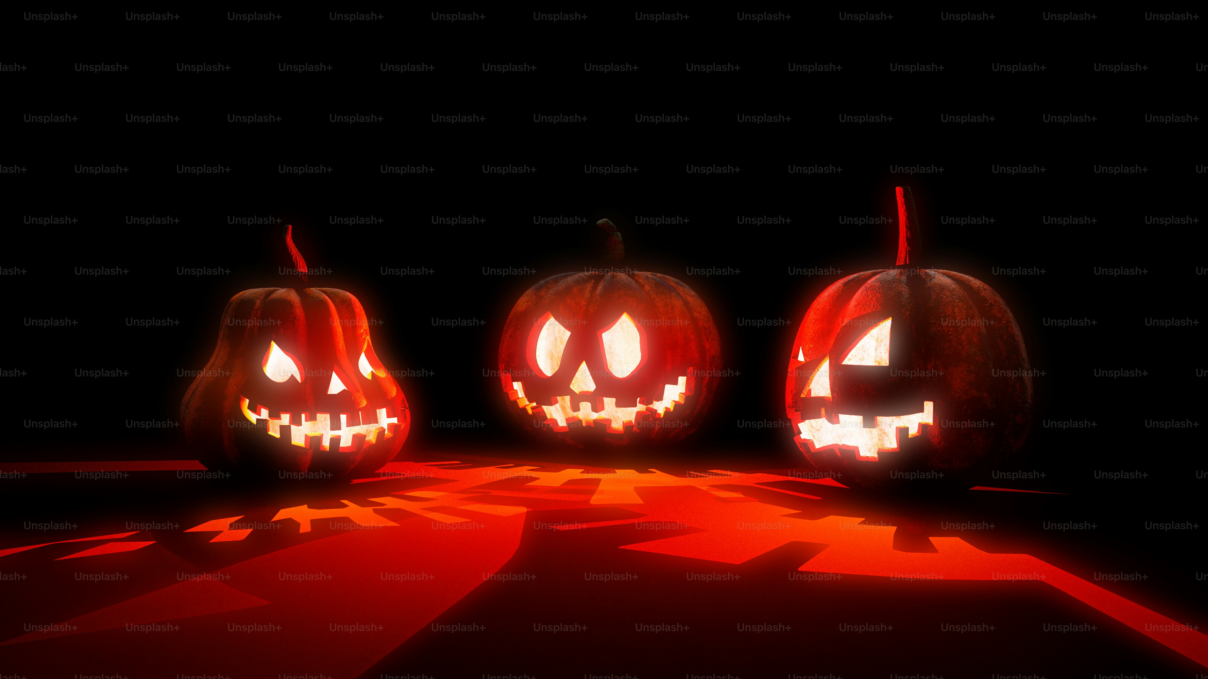 Three carved jack-o'-lanterns glowing with bright red light on a dark surface