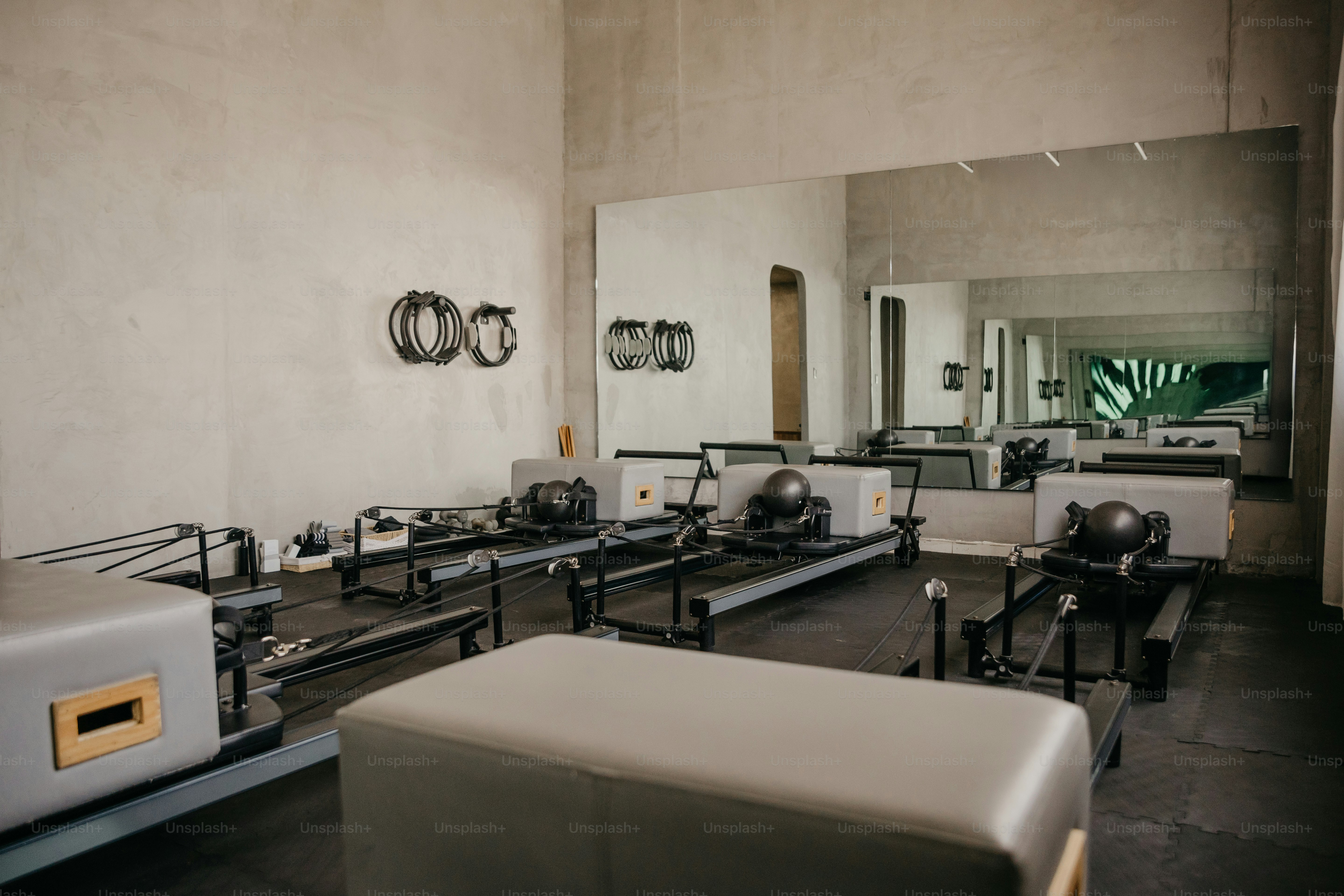 Pilates-Reformer in einem Atelier mit Betonwänden und einem großen Wandspiegel