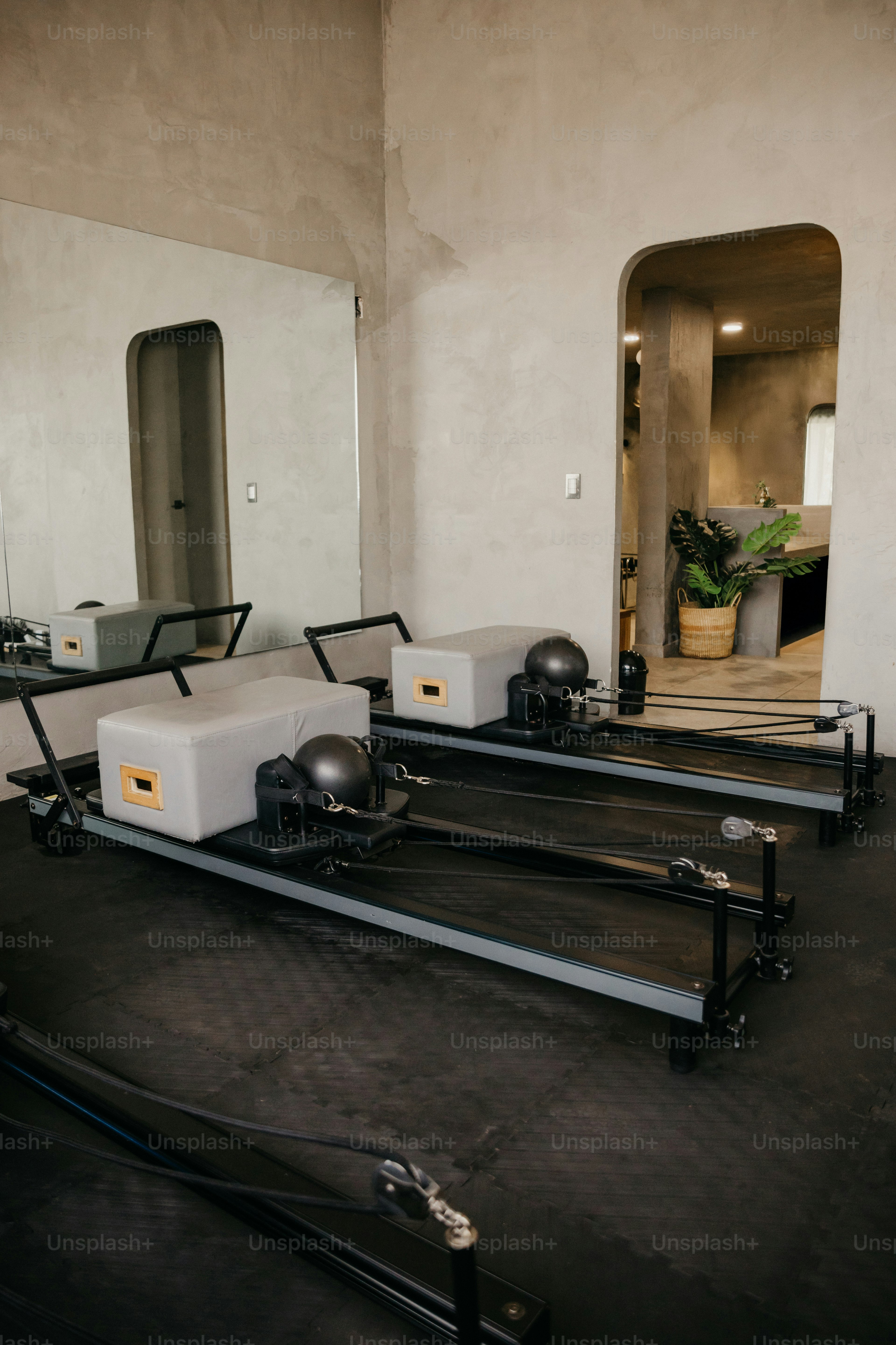 Zwei Pilates-Reformer mit grauen Boxen und schwarzen Bällen in einem minimalistischen Studio