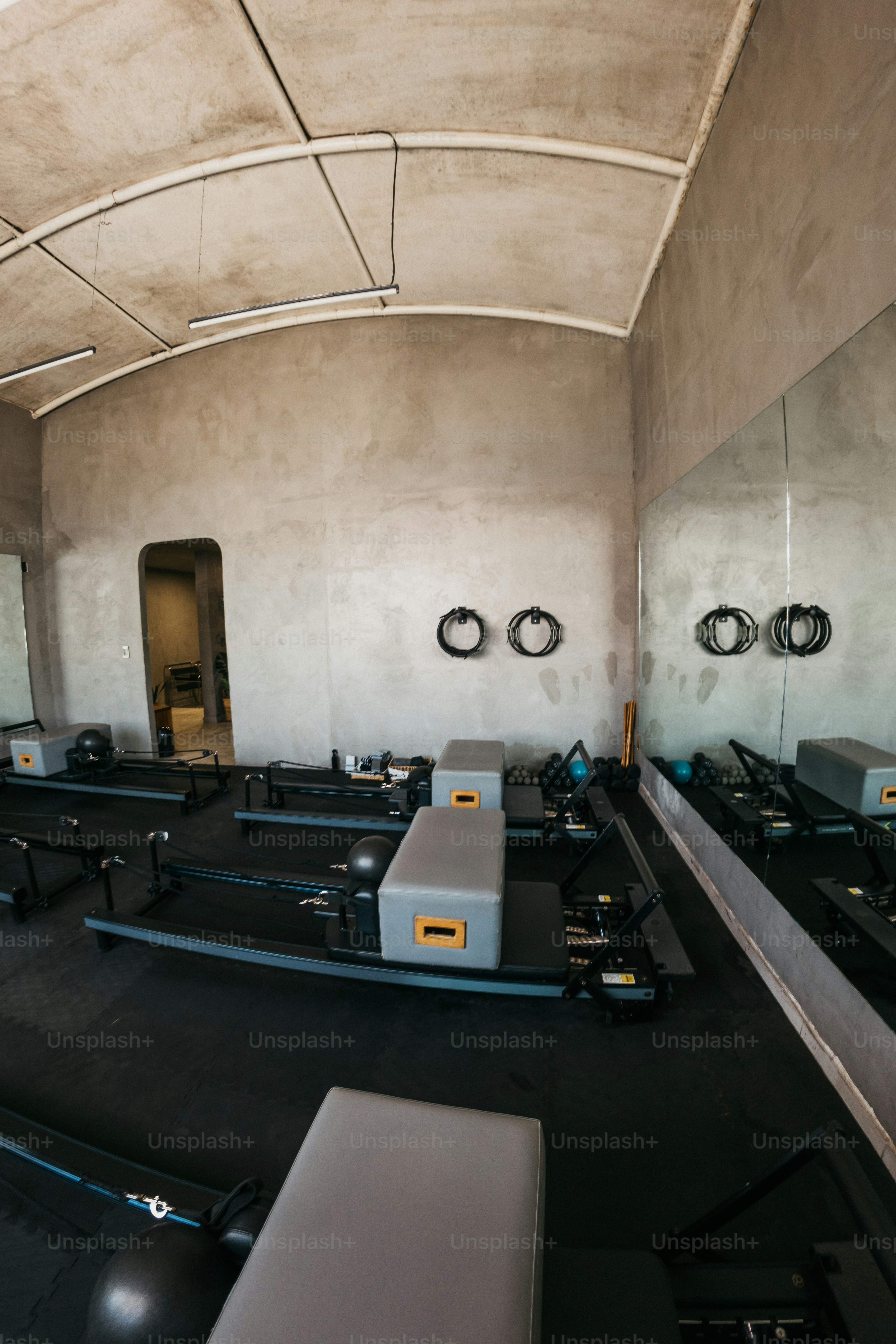 Pilates-Reformer in einem Atelier mit Betonwänden und einem großen Wandspiegel