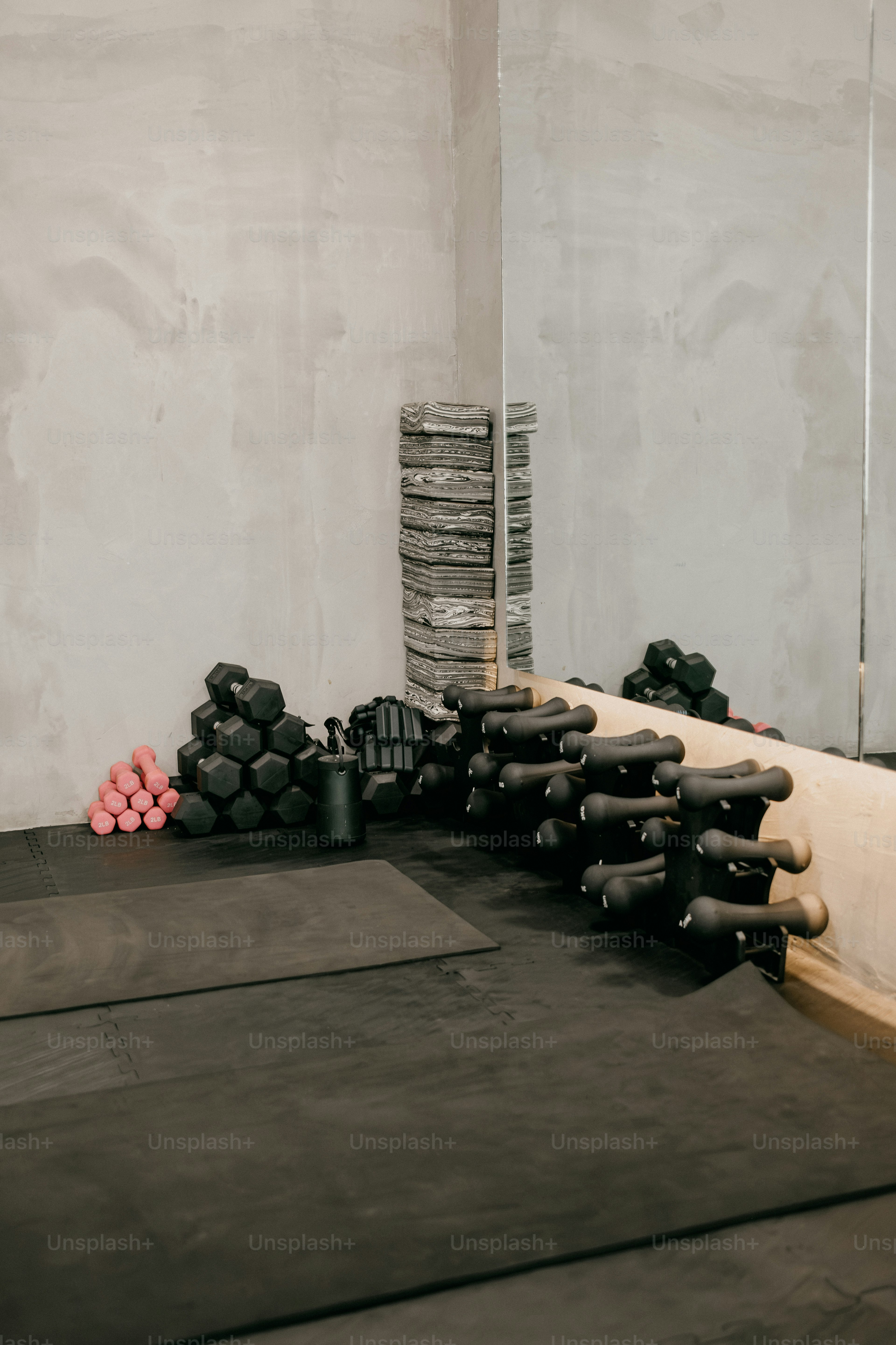 Schwarze und rosa Hanteln mit Yogablöcken auf dem Fitnessboden