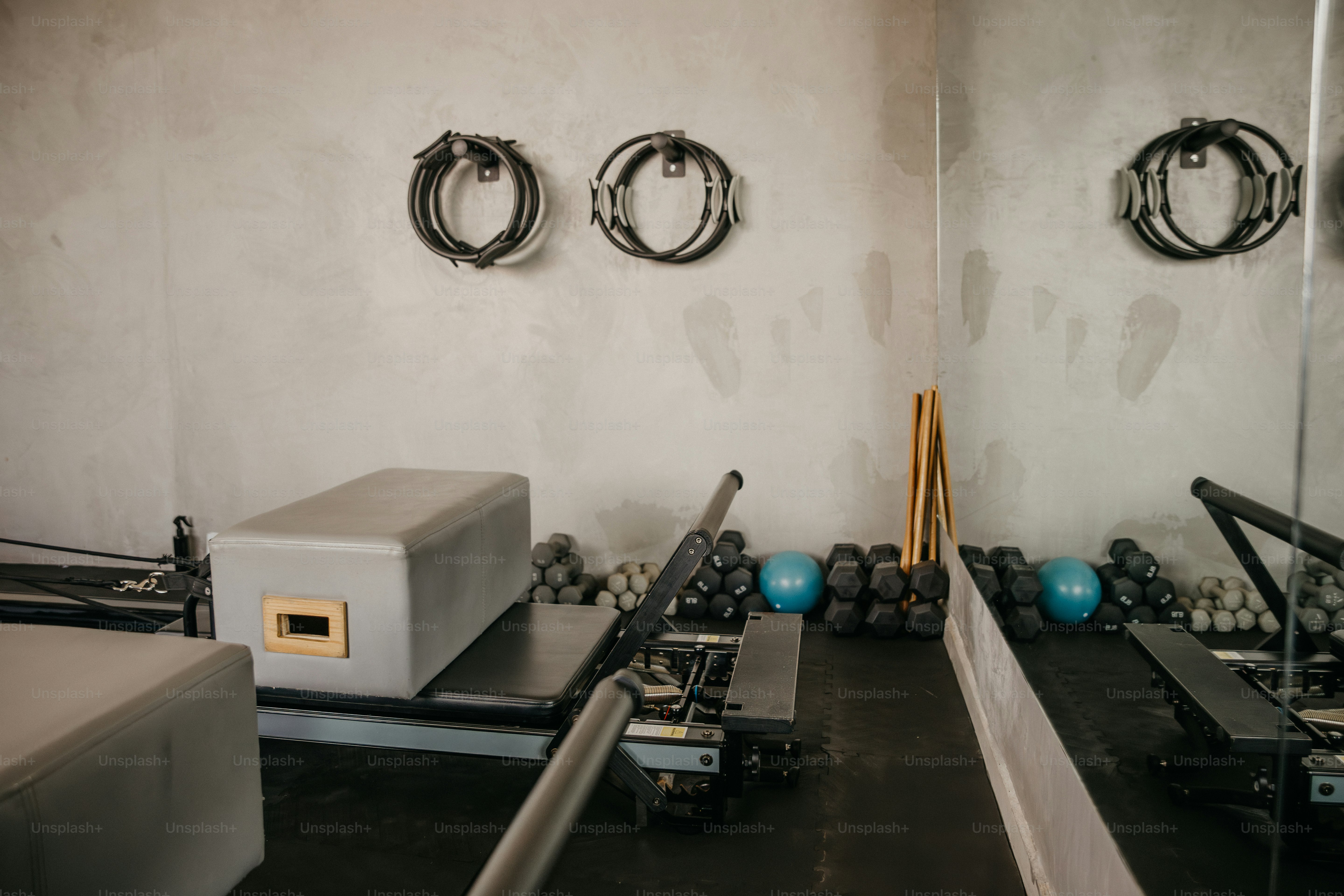 Pilates-Reformer-Gerät mit einer grauen Box in einem Studio mit Fitnessgeräten