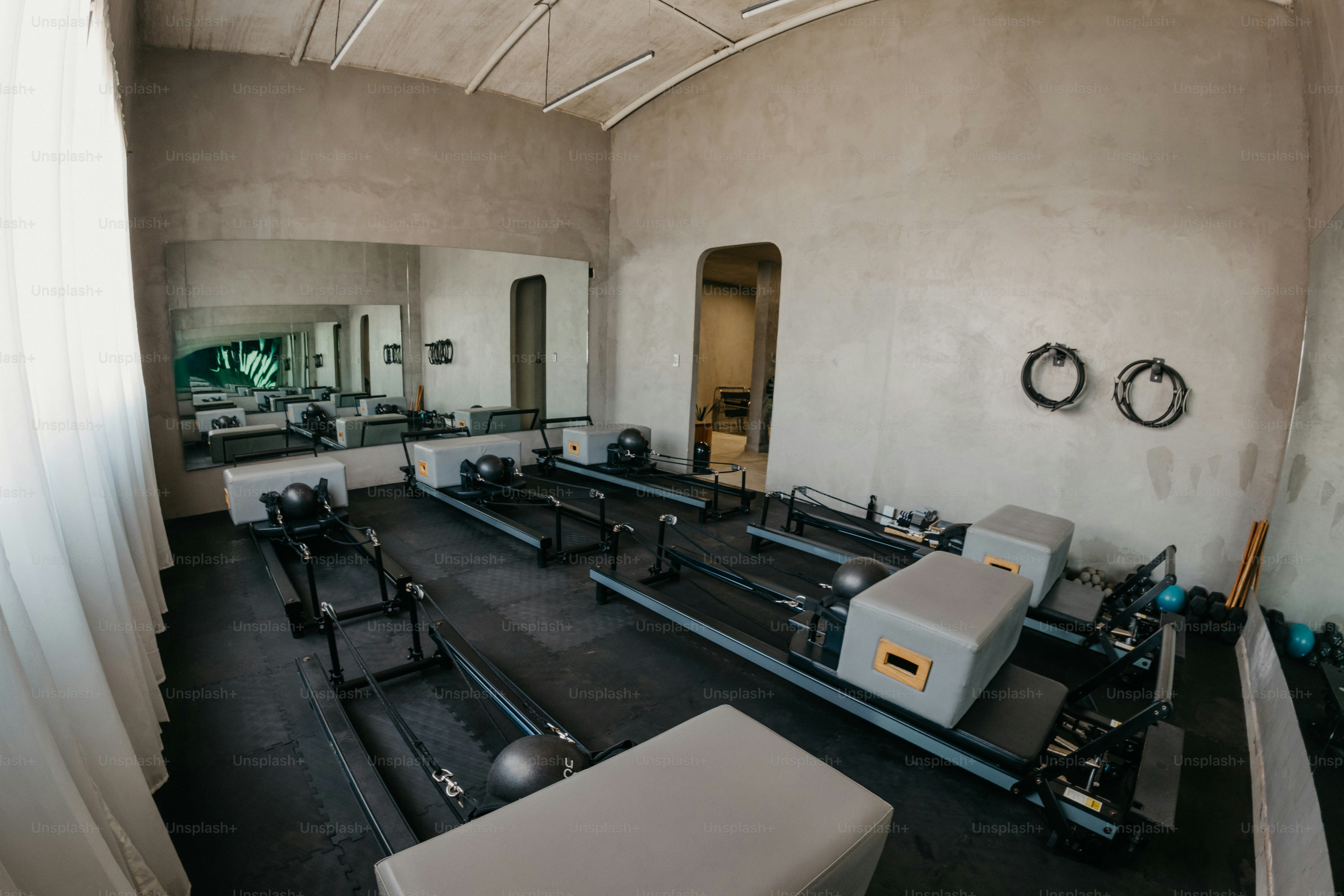 Pilates-Reformer in einem Atelier mit Betonwänden und einem großen Wandspiegel