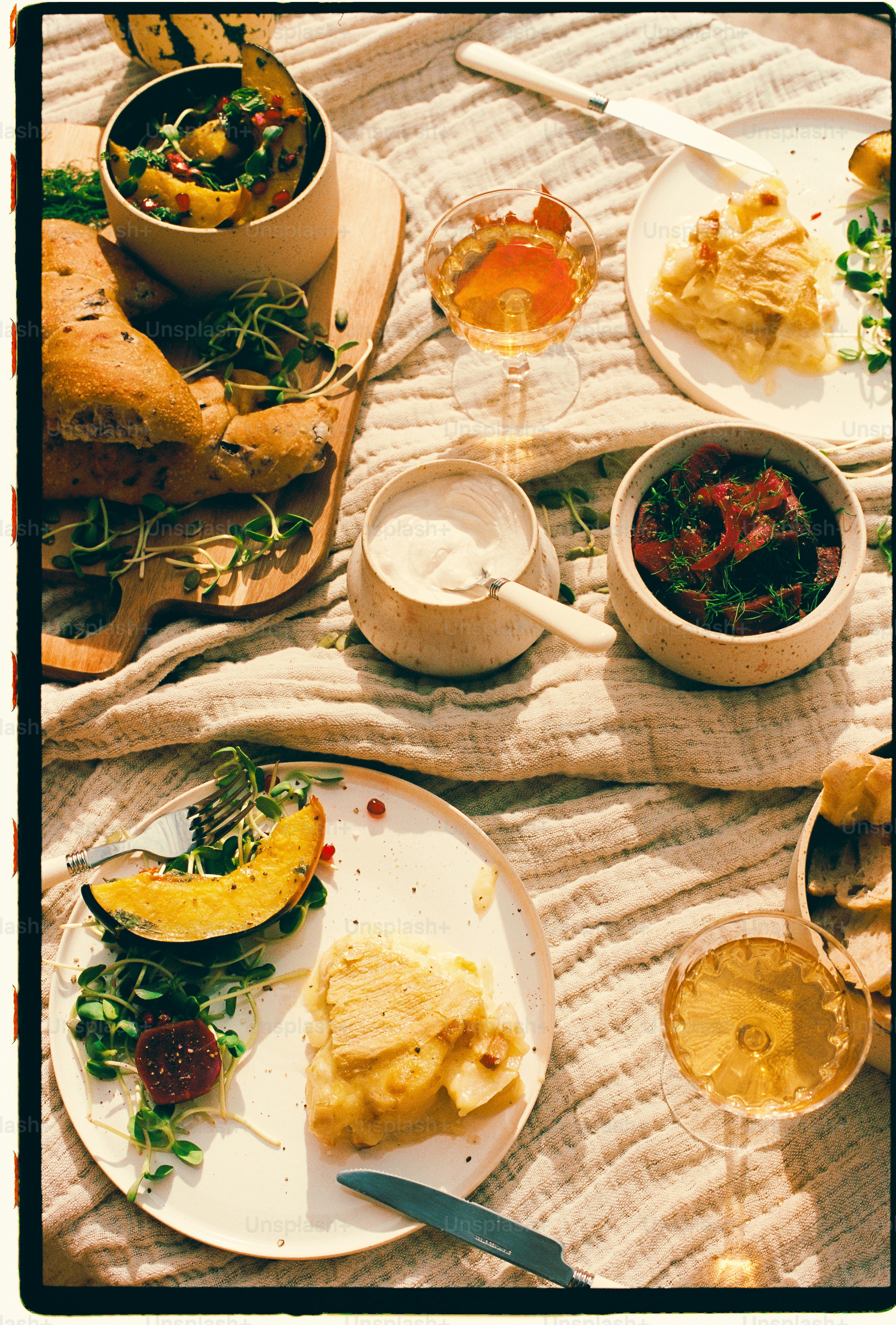 Un panno da picnic con zucca arrosto, gratin di patate, pane e vino su un panno