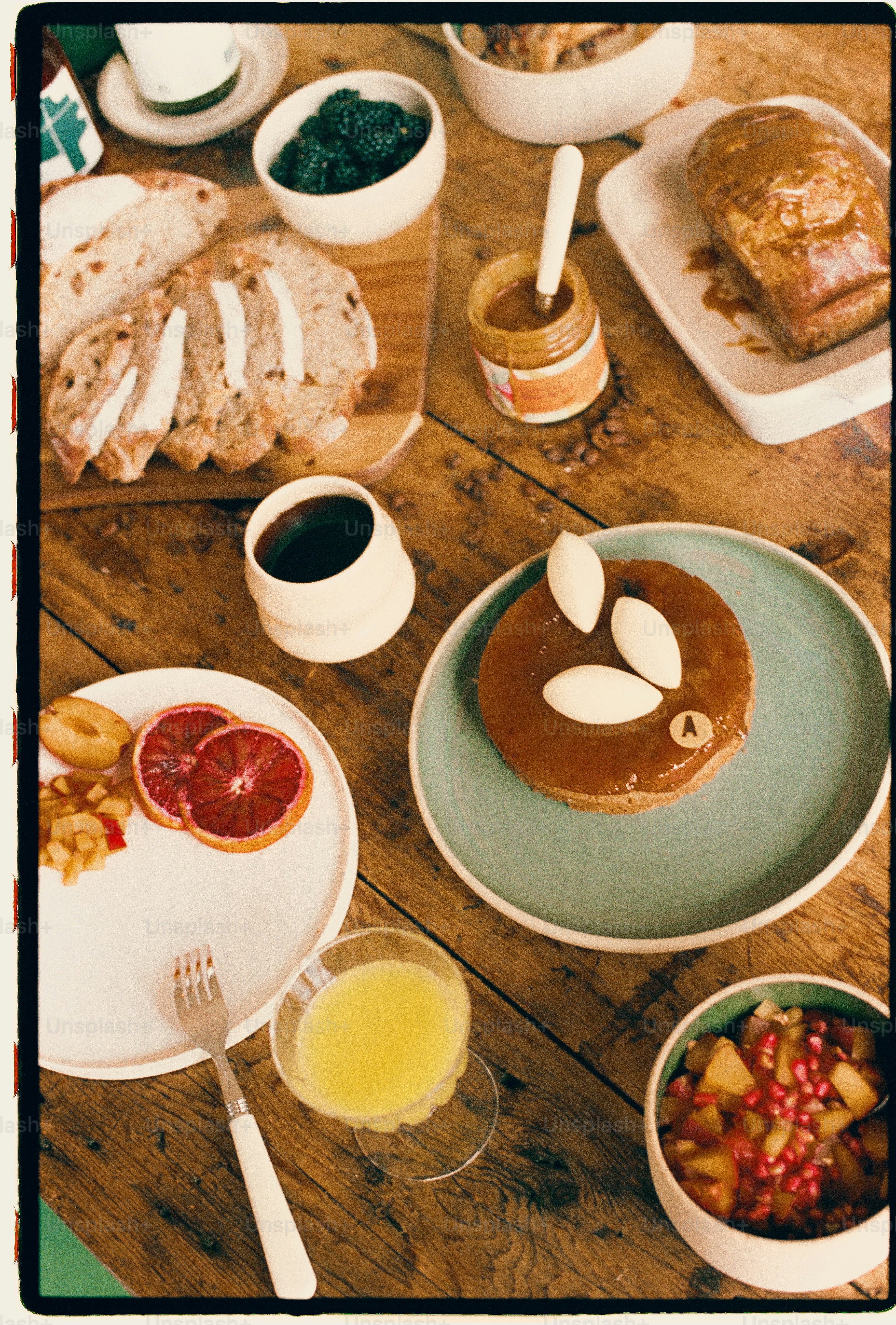 Una colazione spalmata con pane, frutta, caffè e una crostata su un tavolo di legno