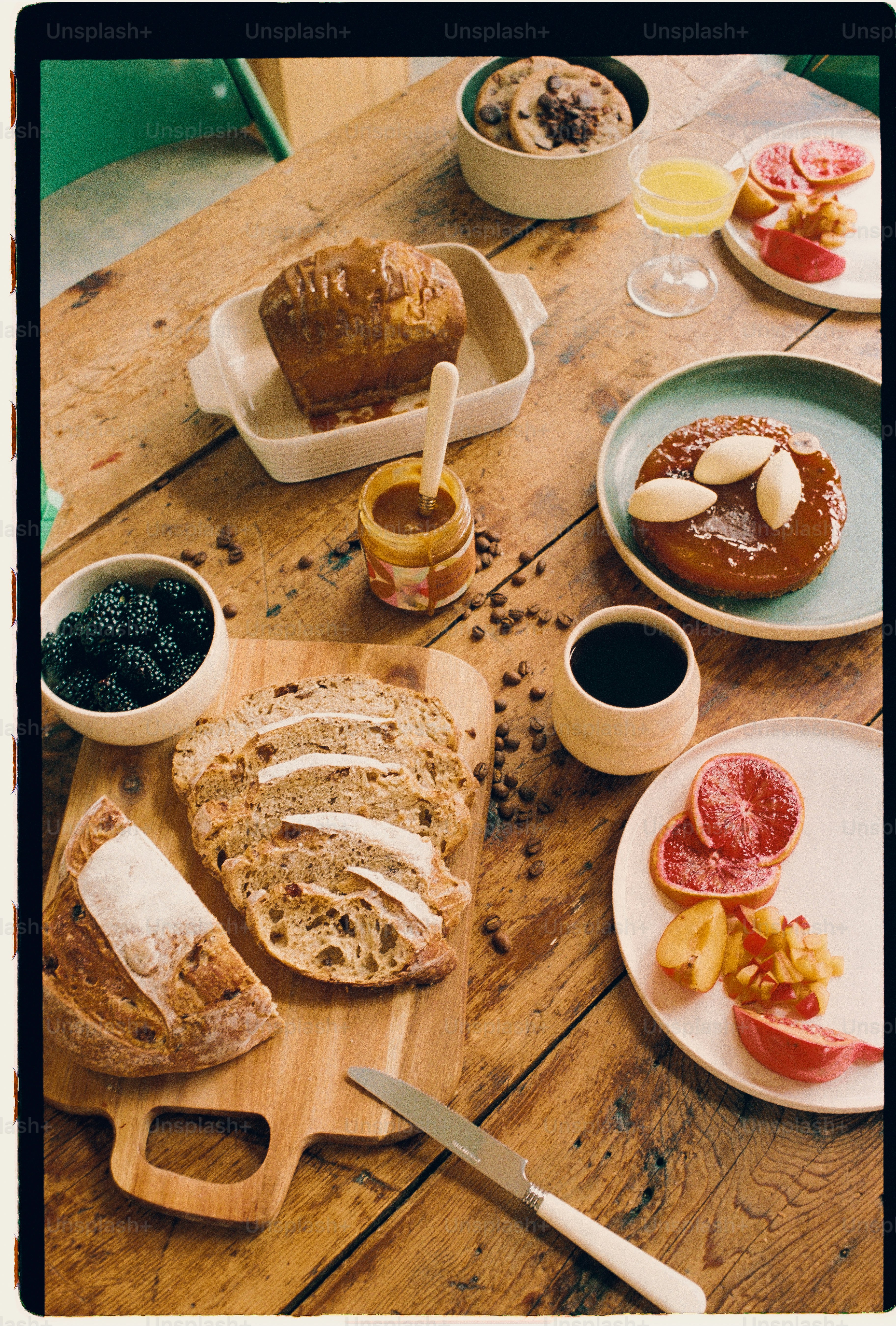 Una colazione rustica spalmata con fette di pane, frutta, dolci e caffè su un tavolo di legno