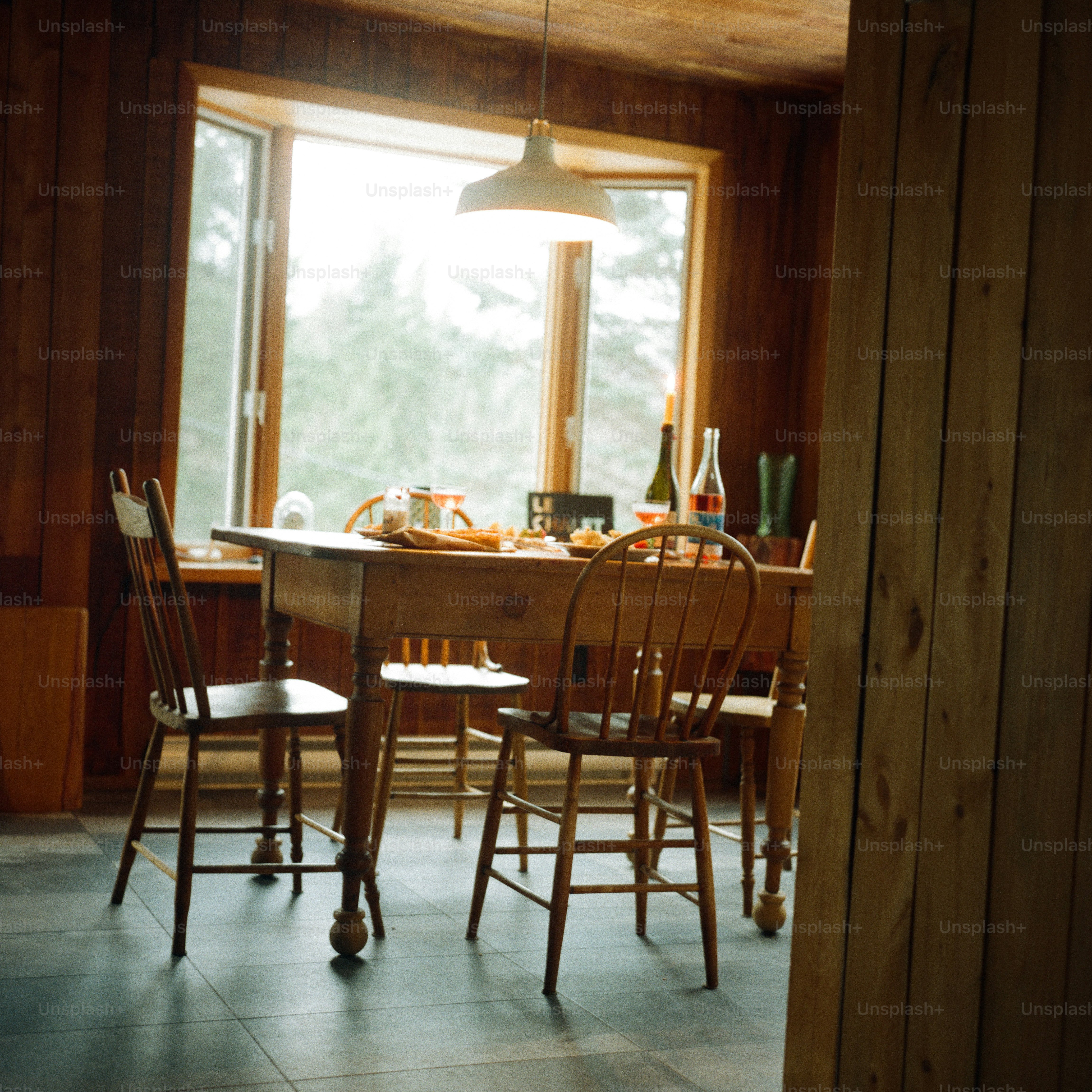 Un tavolo da pranzo in legno con sedie in una stanza illuminata dal sole con pannelli di legno