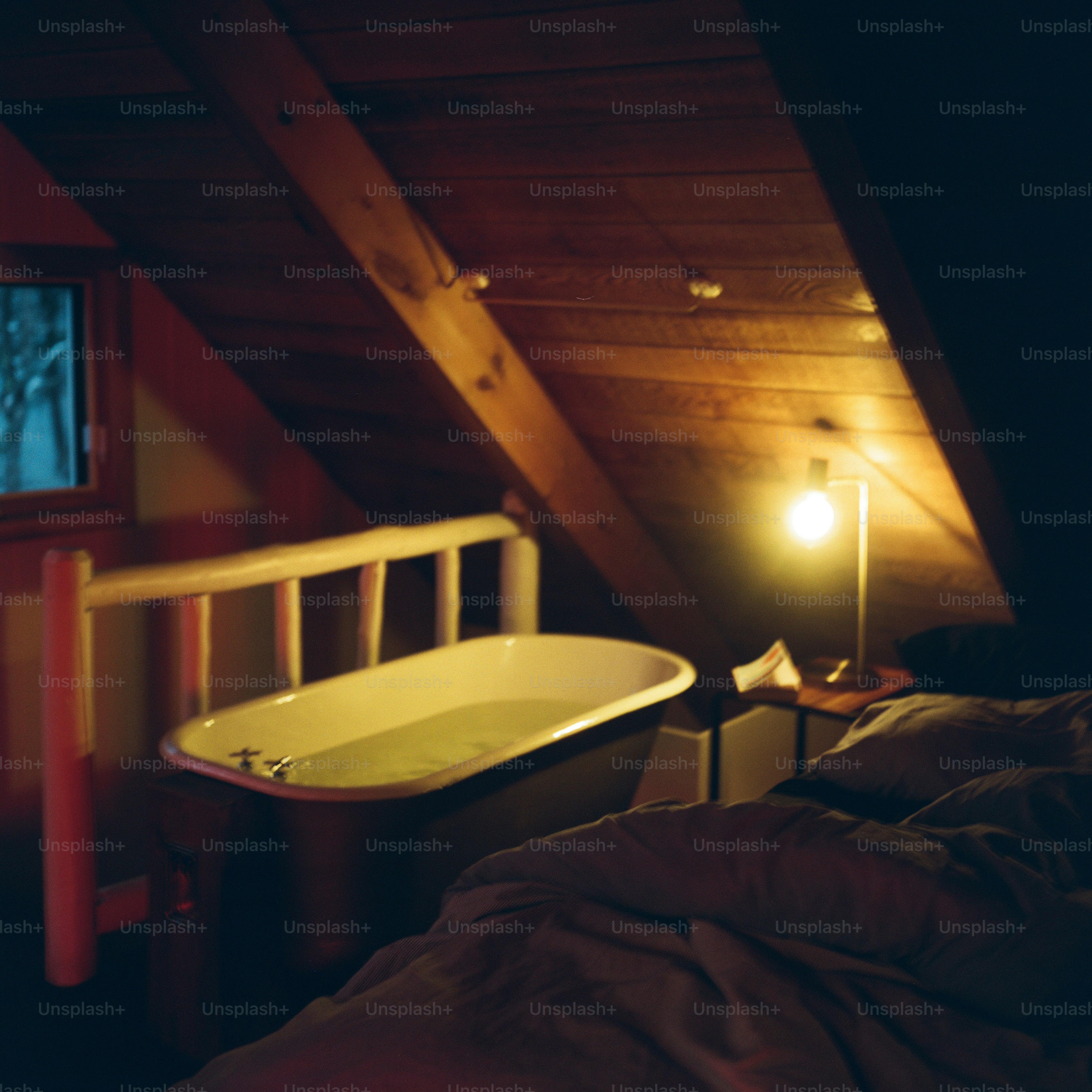 Una vasca da bagno in una camera da letto con soffitto in legno e una lampada calda