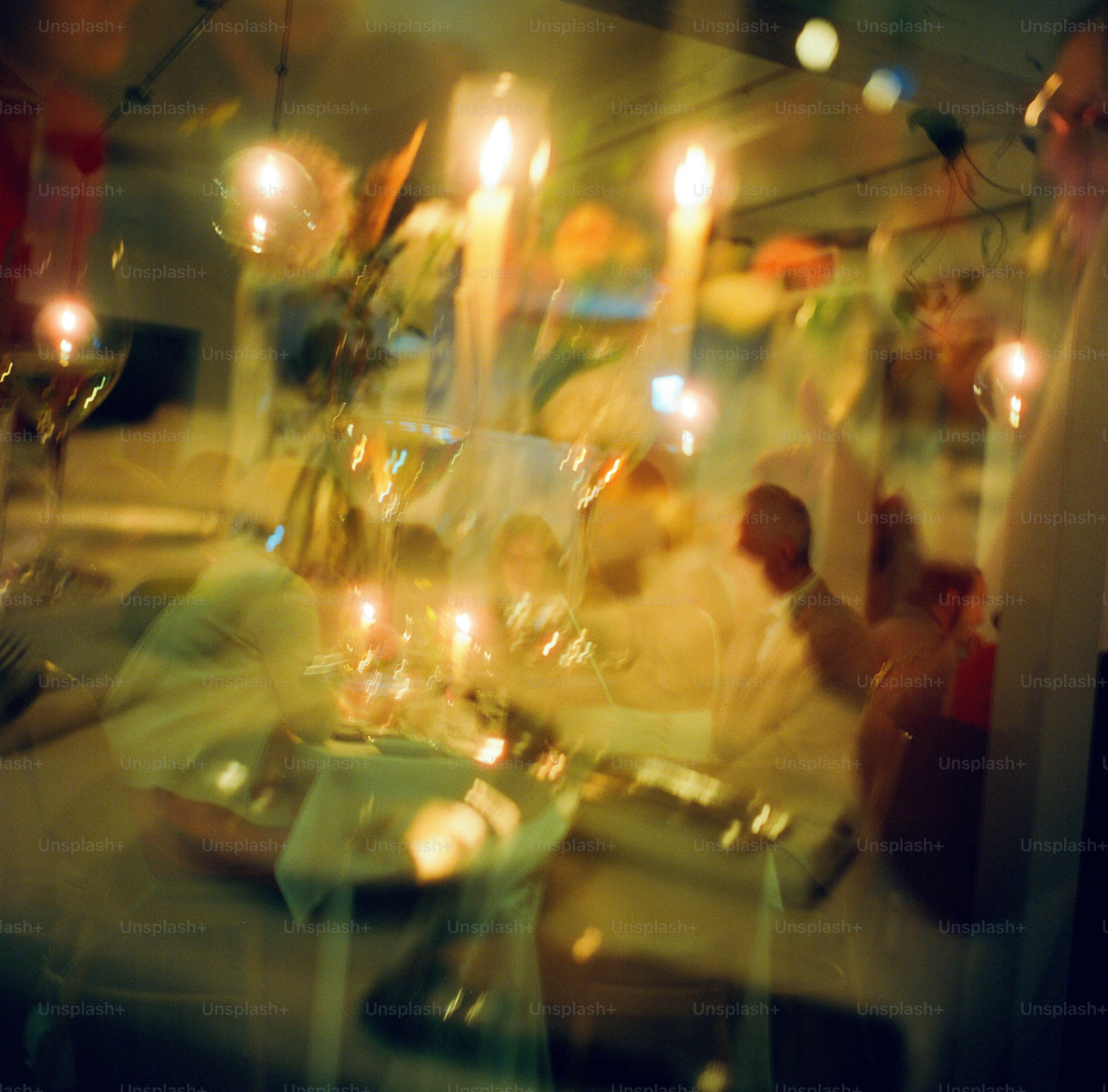 Vista sfocata di una cena a lume di candela con bicchieri di vino e persone