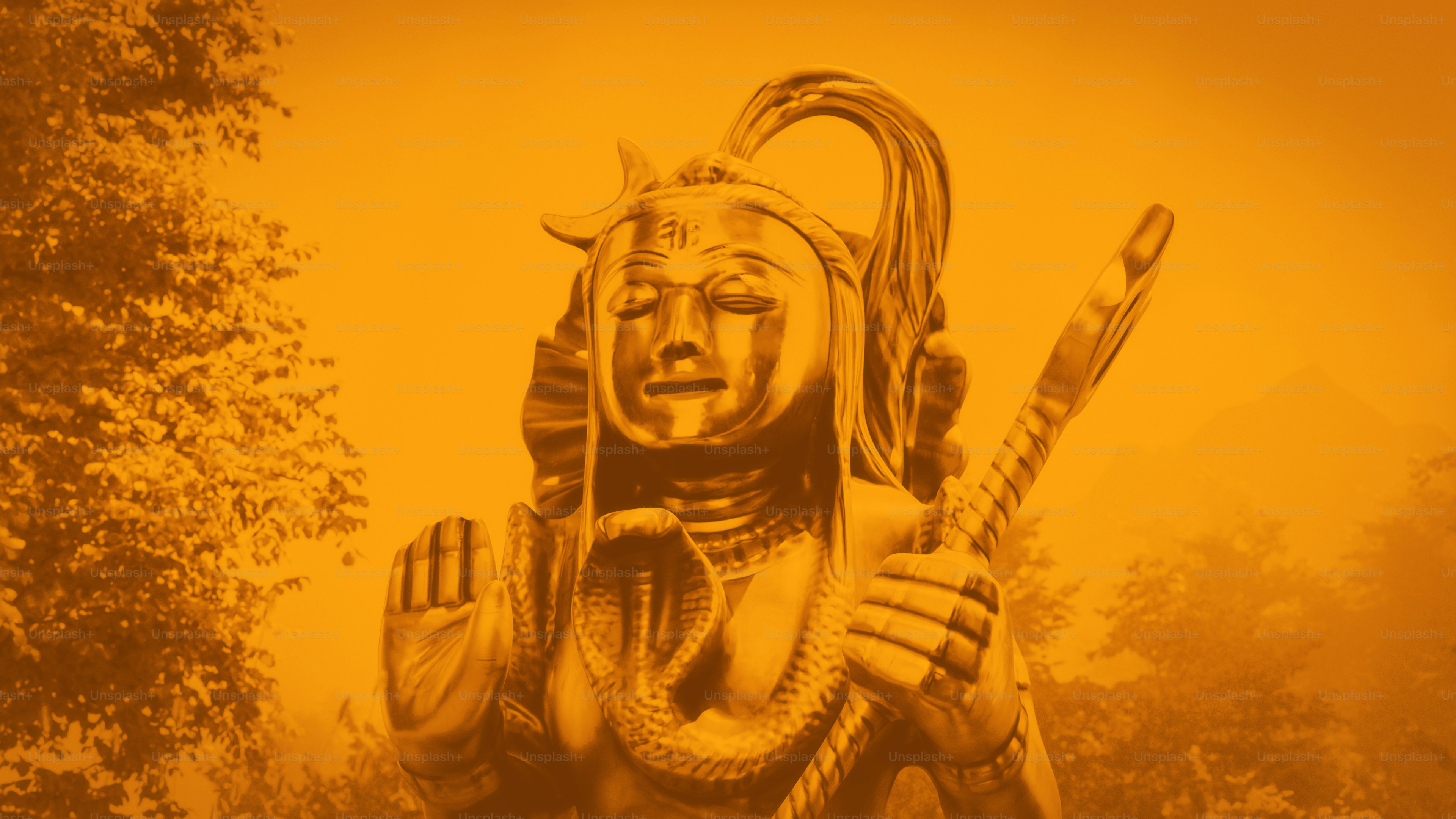 A golden statue of Shiva with a cobra and trident against trees