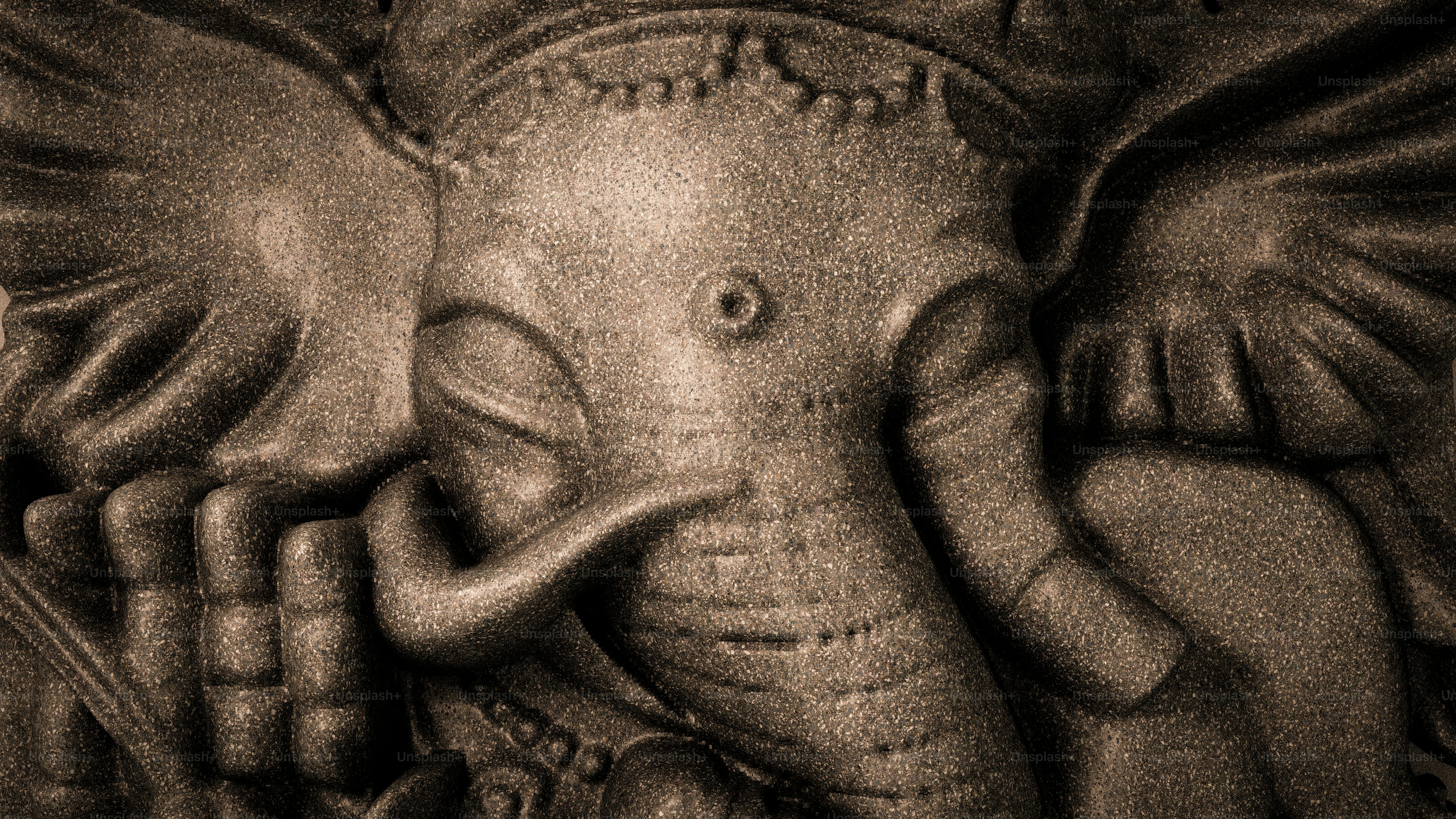 A close-up of a textured stone carving of the Hindu deity Ganesha