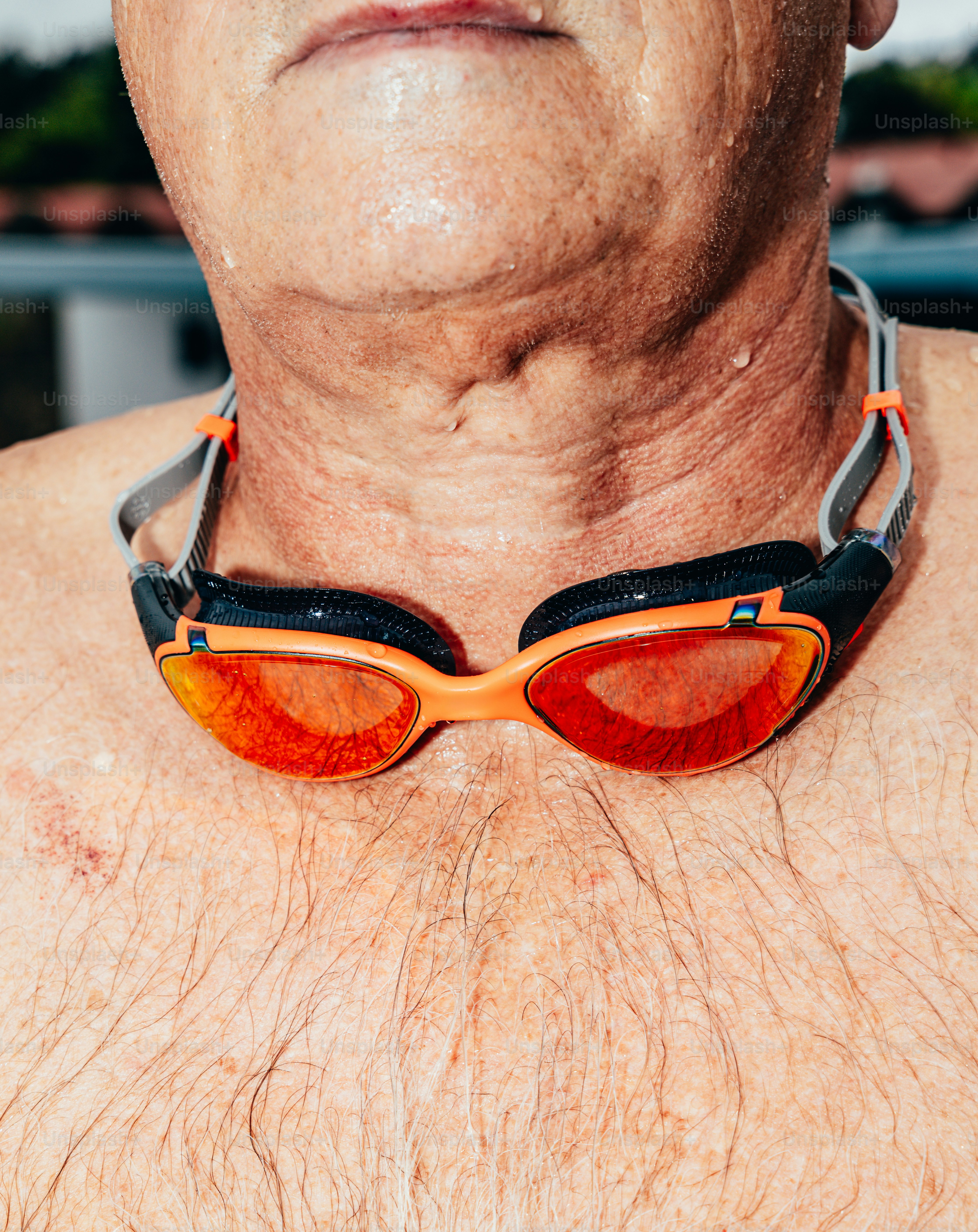 Una persona con la piel mojada que lleva gafas de natación naranjas alrededor del cuello