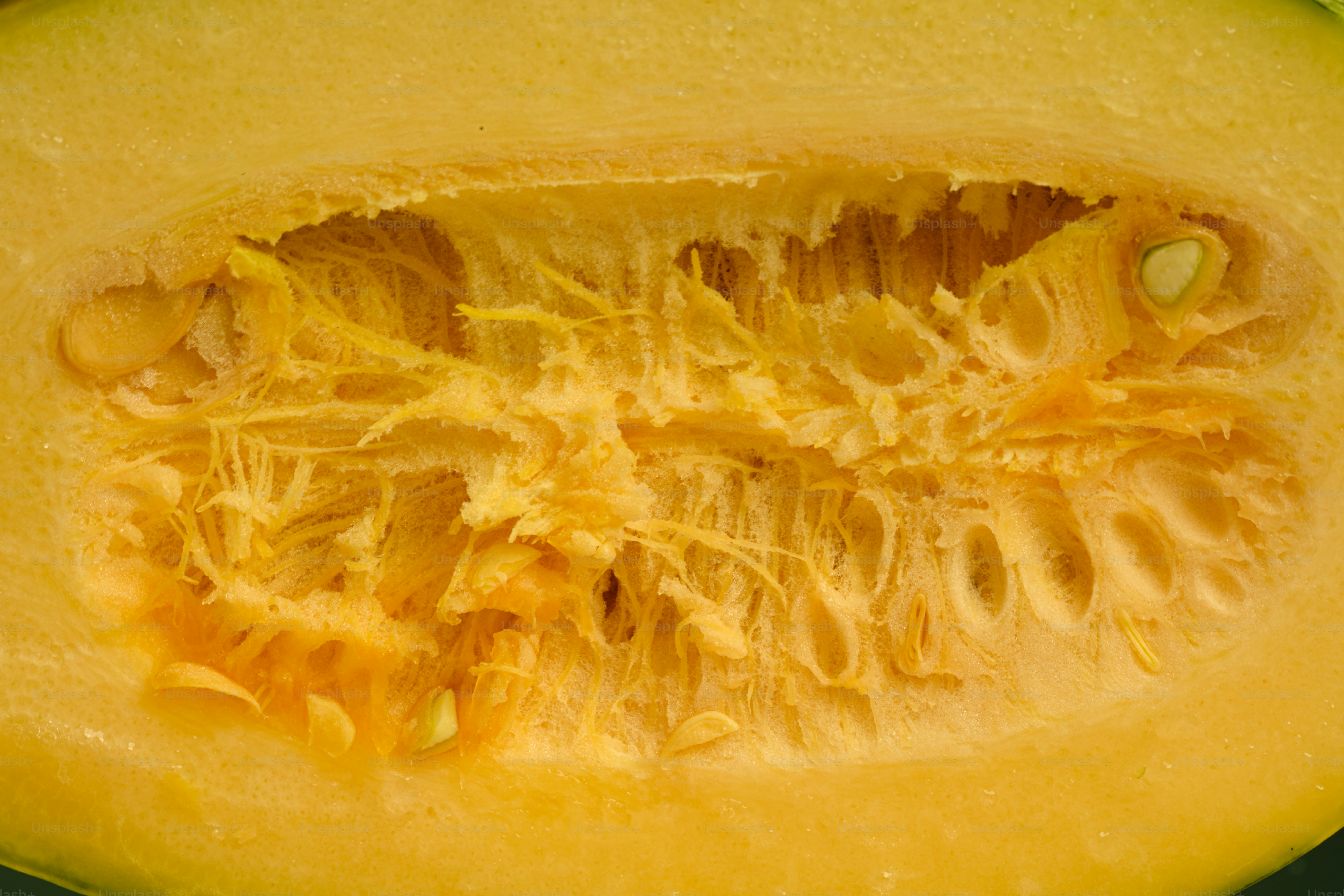 A close-up of the fibrous yellow interior and seeds of a halved squash