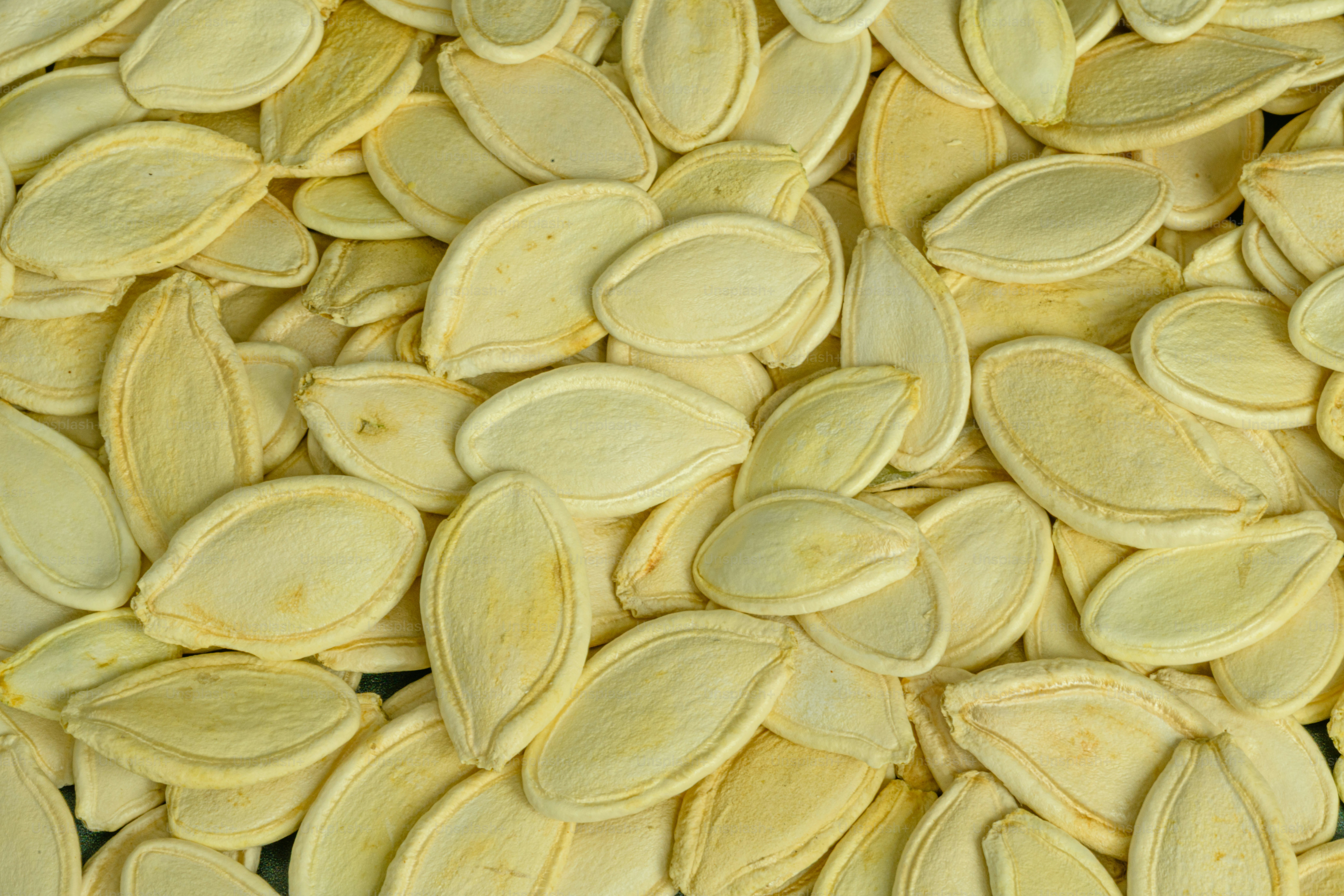 A dense pile of pale yellow pumpkin seeds filling the frame