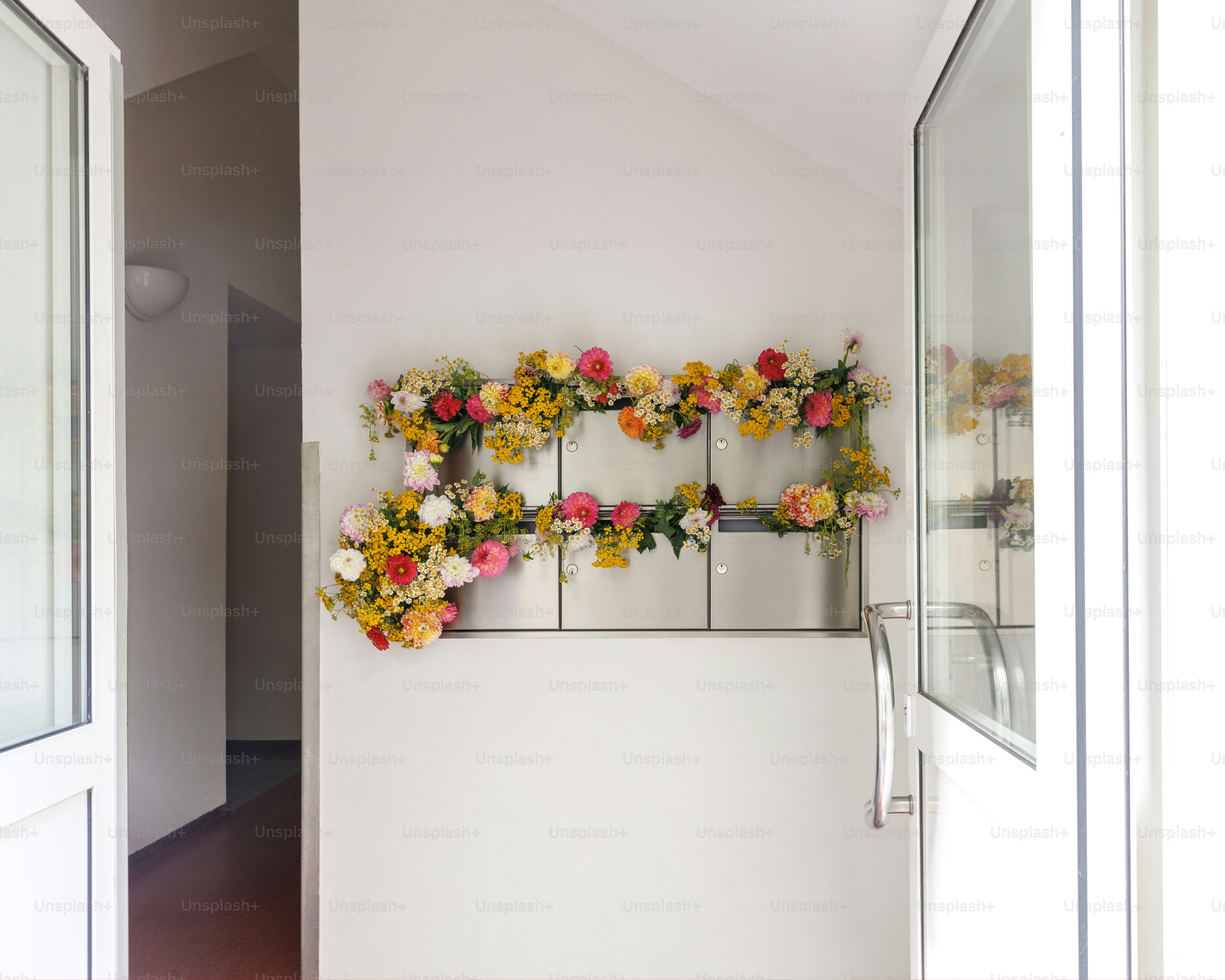 A wall of metal mailboxes decorated with colorful fresh flowers in a hallway