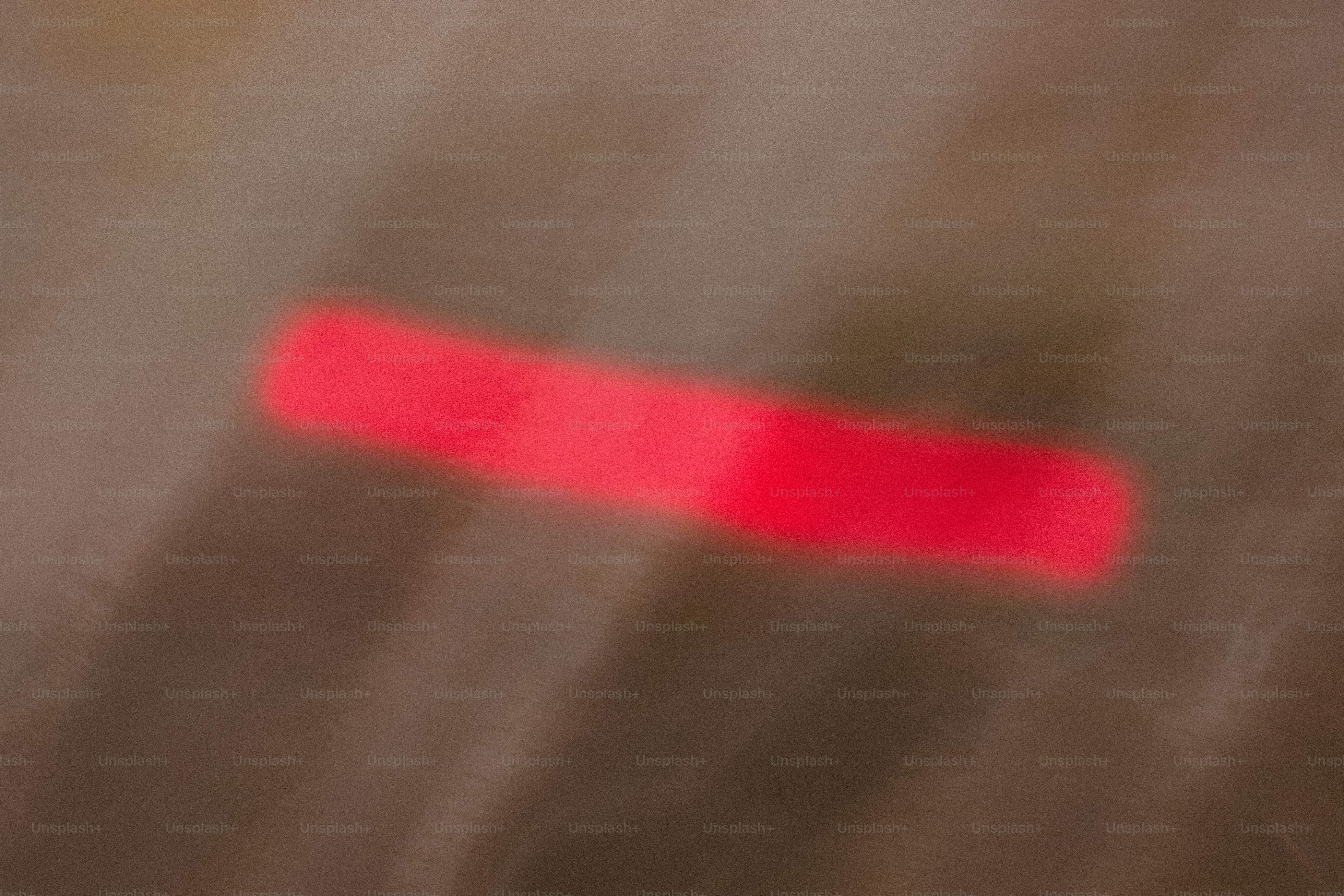 A blurred horizontal red light streak against a dark brown background