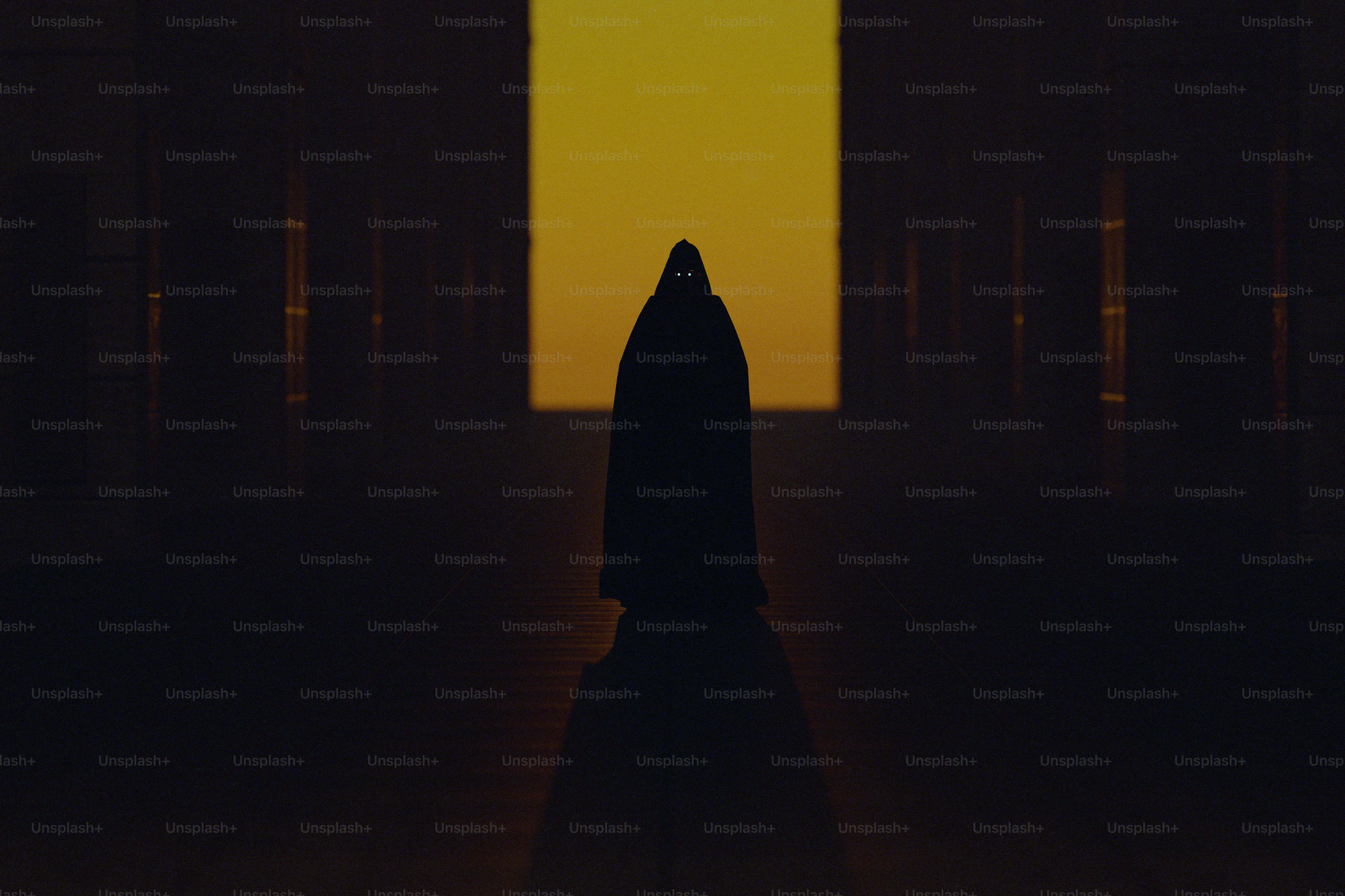 A hooded silhouette with glowing eyes against a bright yellow rectangular light