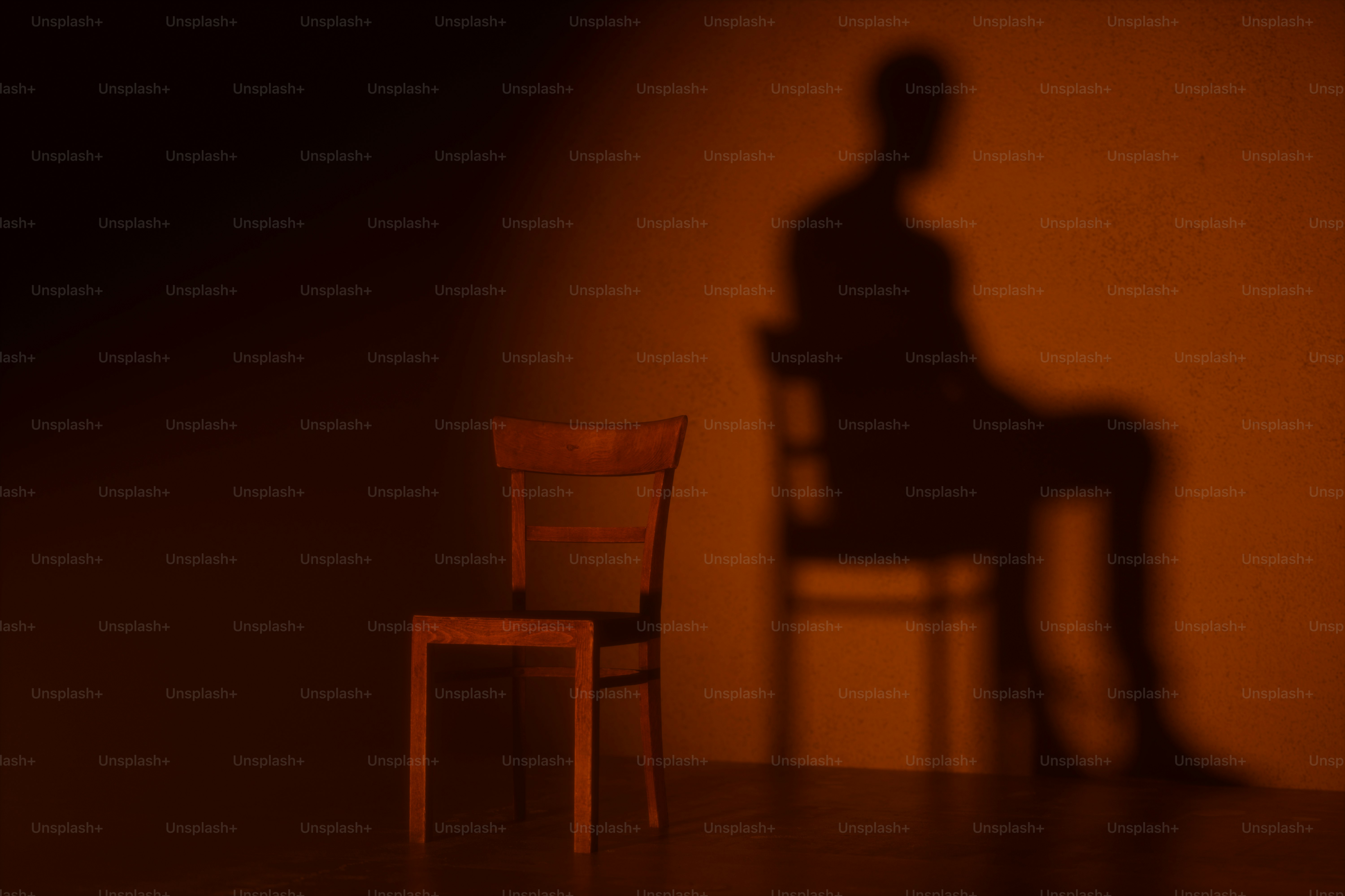 A wooden chair beside a dark silhouette of a person on a wall