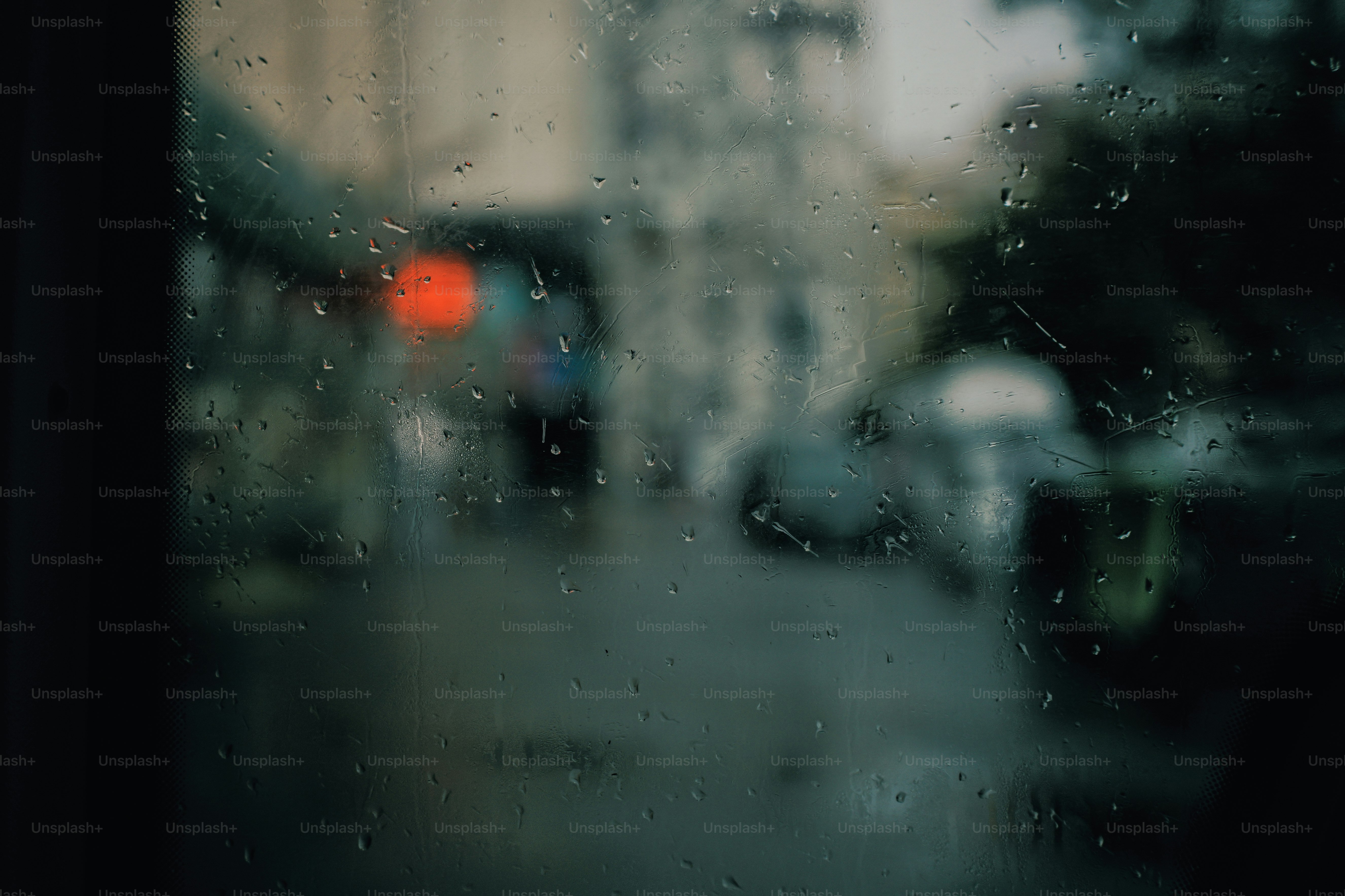 Raindrops on a window pane with a blurred city street in the background