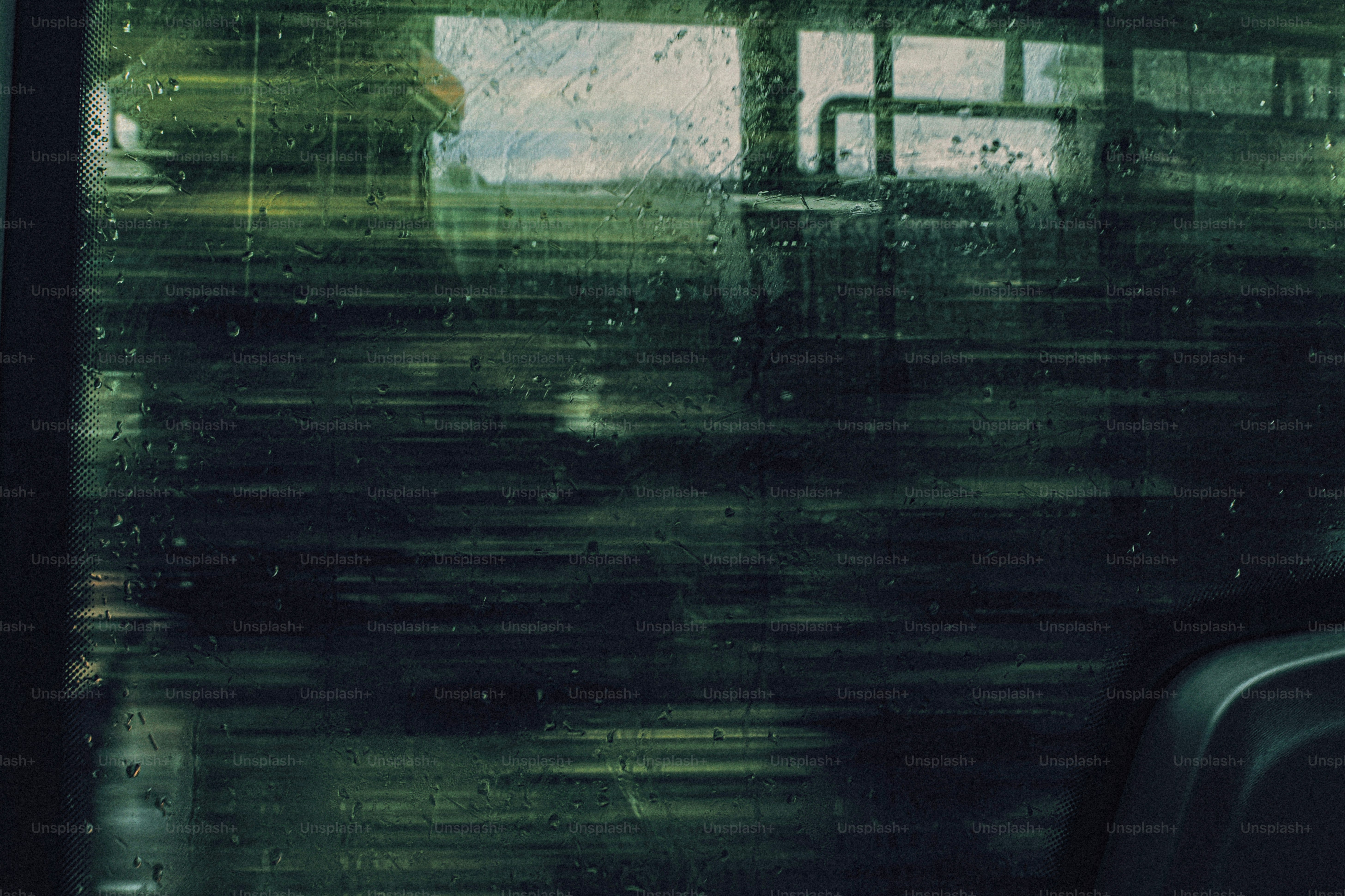 Raindrops on a dark window pane with a blurred landscape outside
