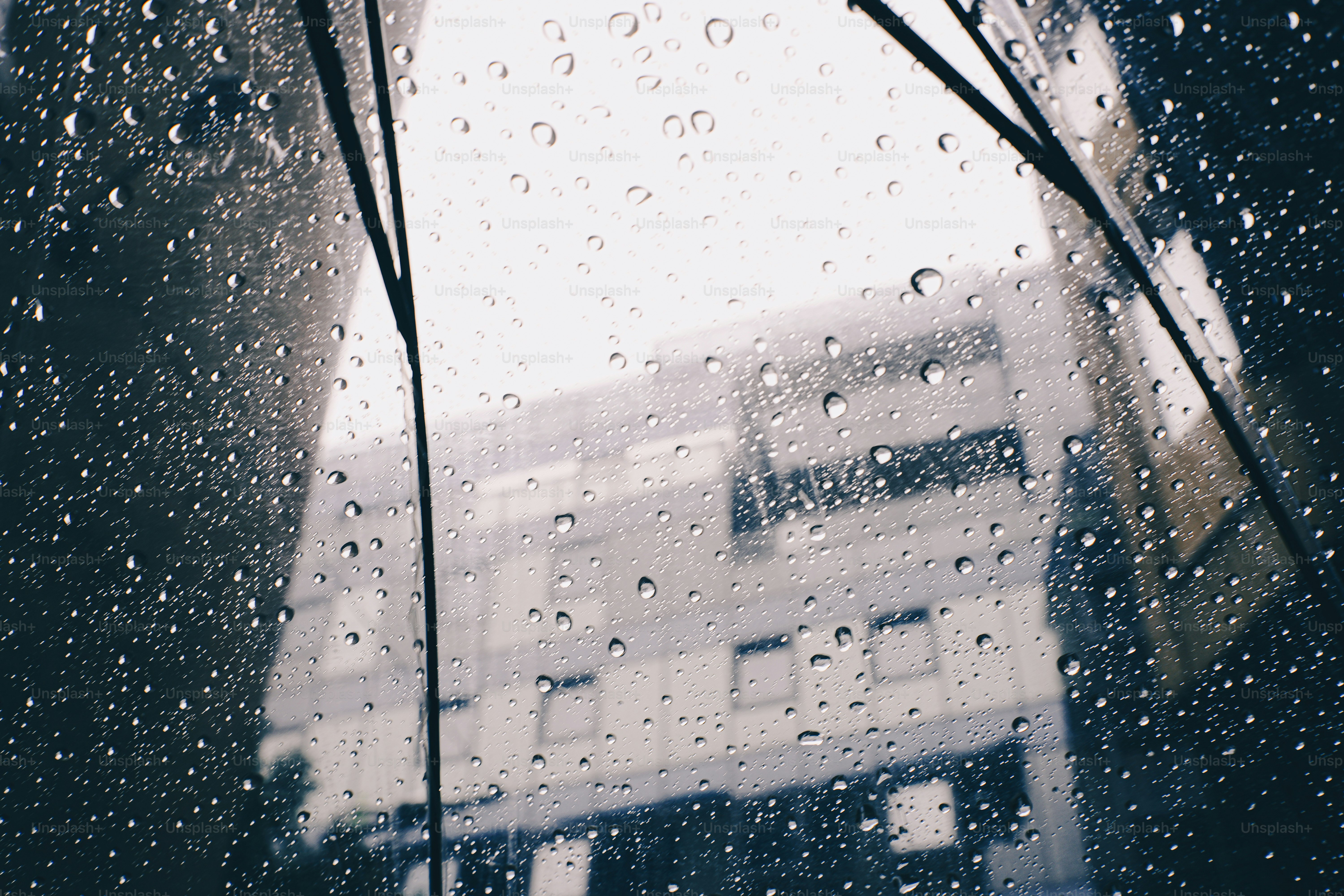 Raindrops on a clear umbrella surface with a blurred building in the background