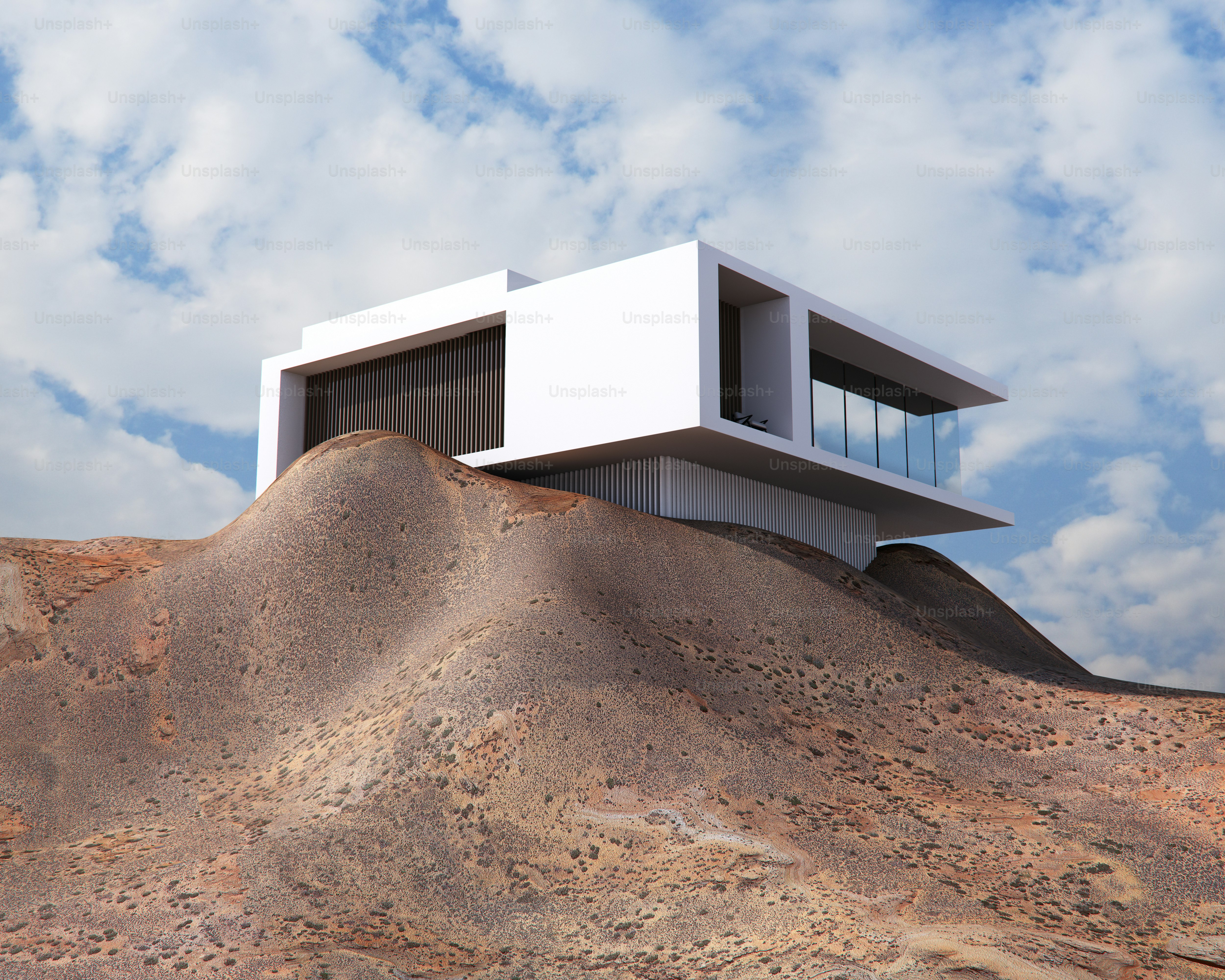 Una casa blanca moderna con paredes de cristal situada en una colina desértica y árida