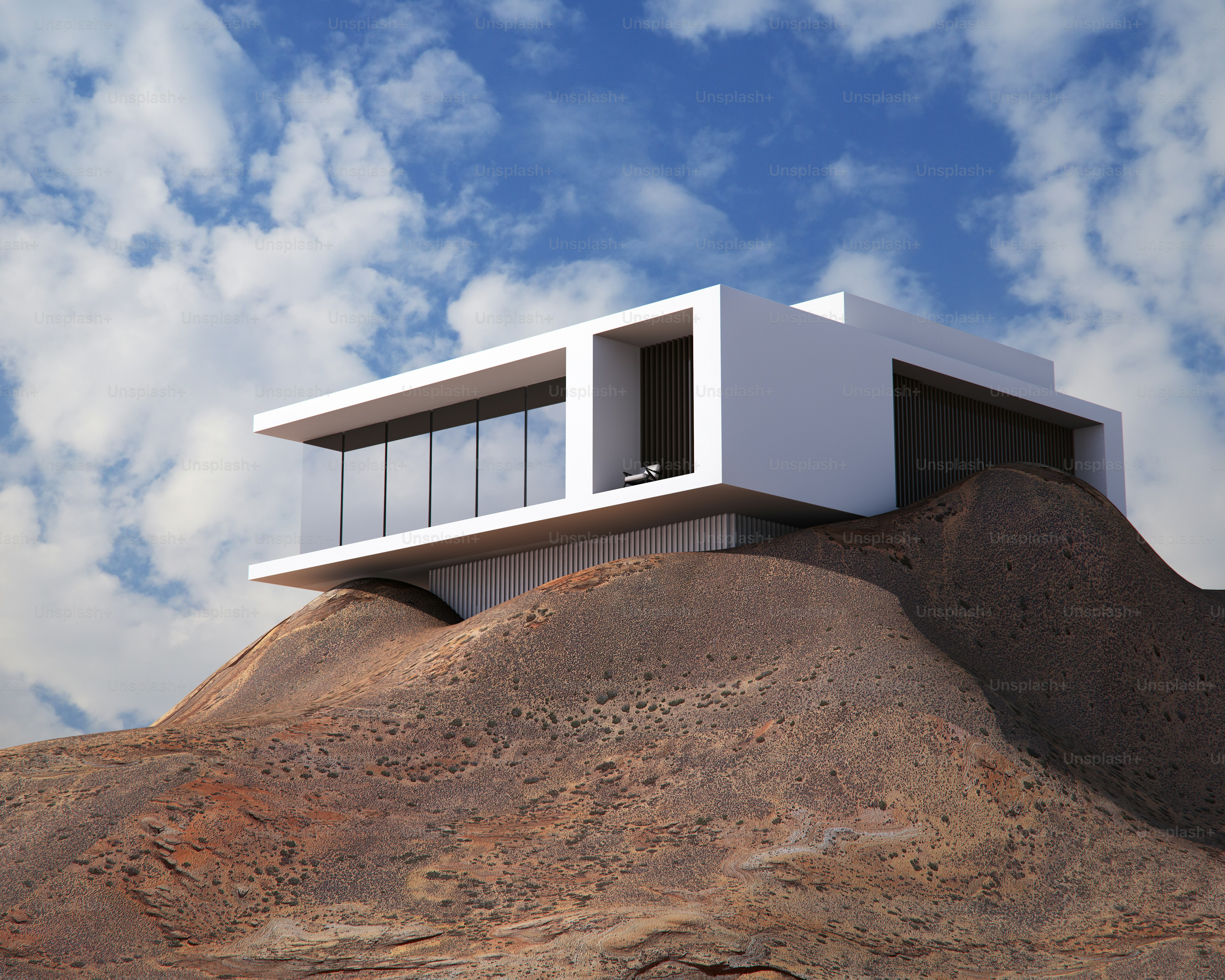 Una casa blanca moderna con grandes ventanales de cristal situada en una colina rocosa