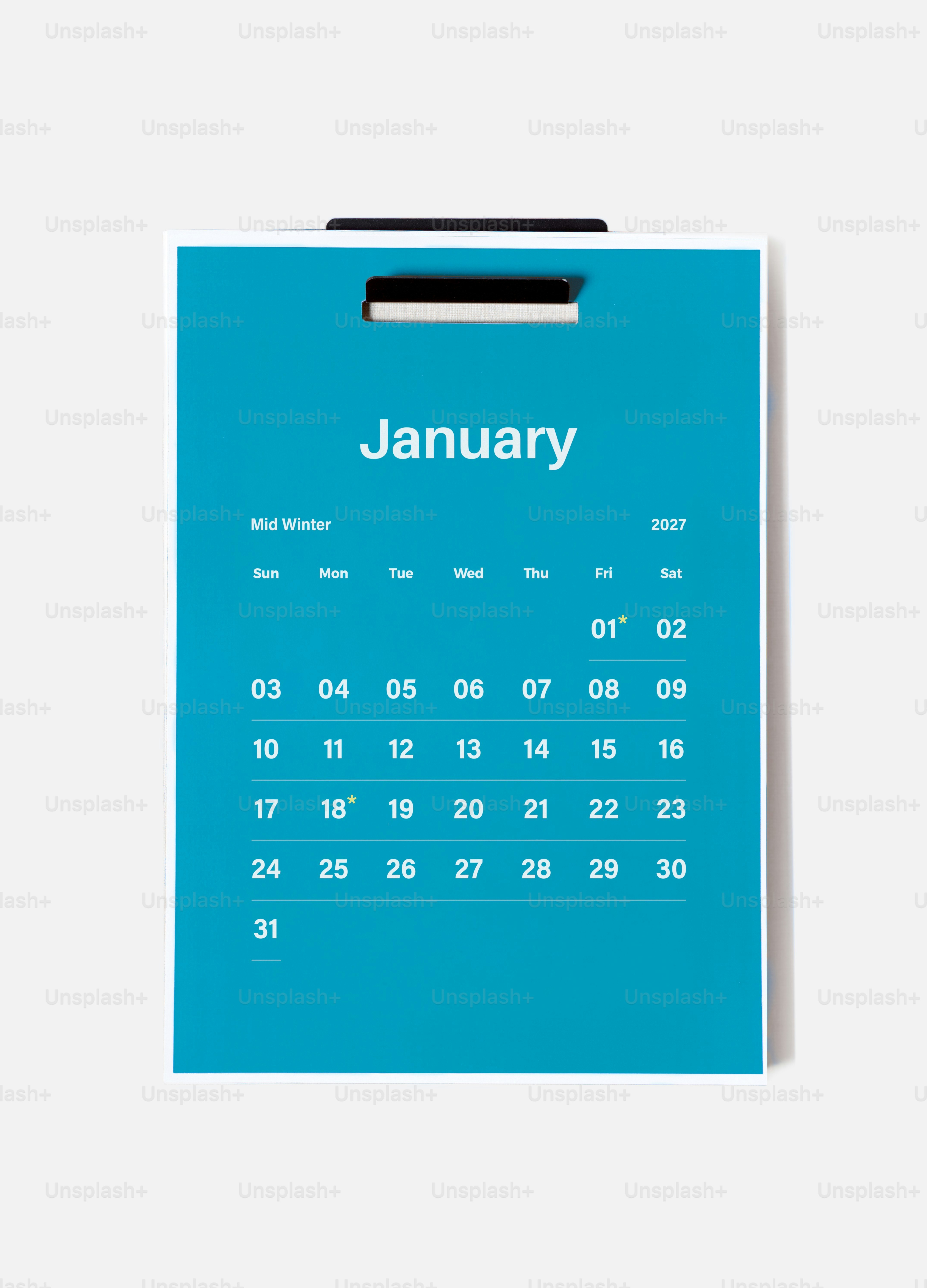 Ein blauer Wandkalender für Januar 2027, der auf einer schlichten weißen Oberfläche hängt