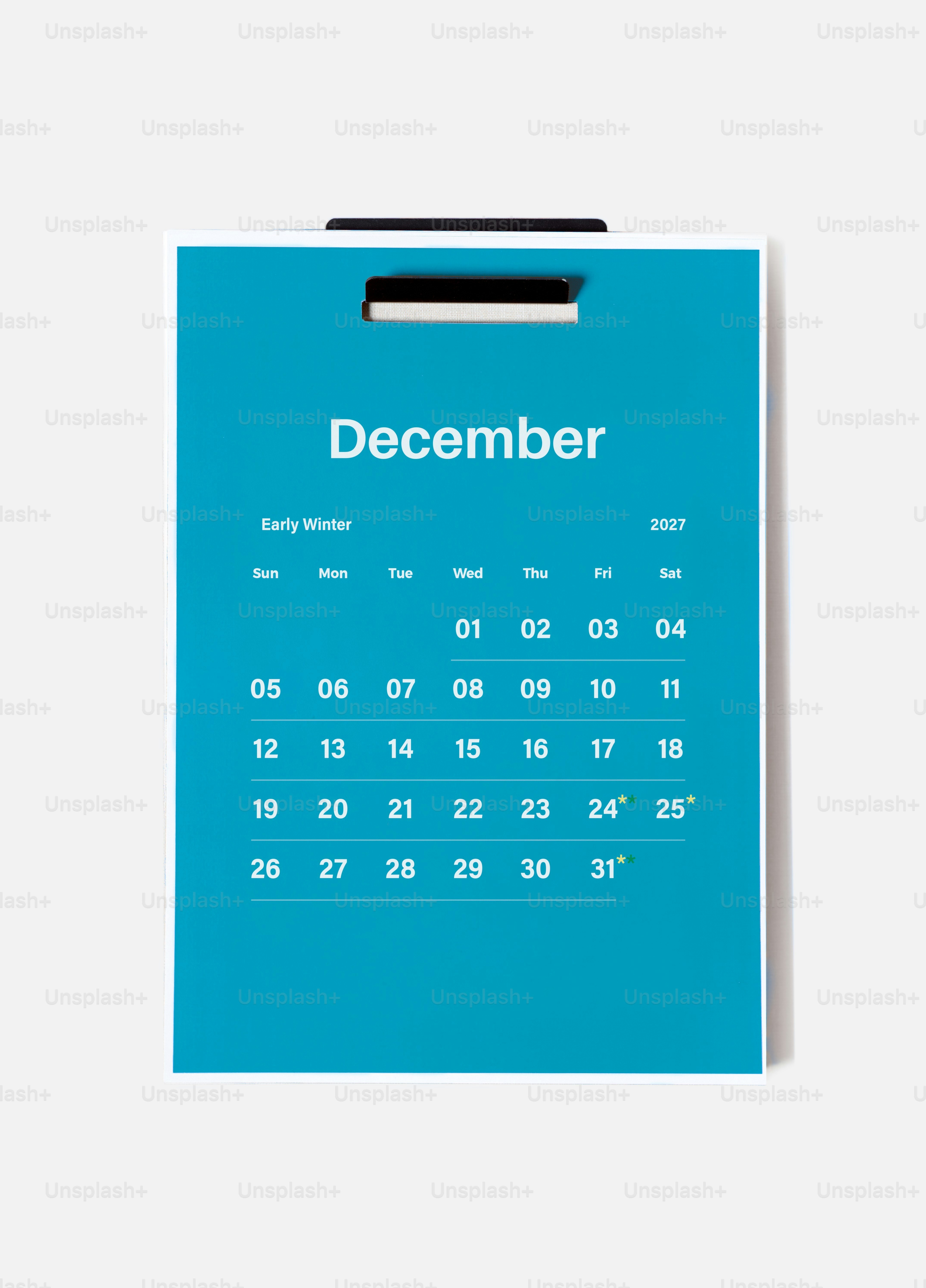 Ein blauer Wandkalender für Dezember 2027, der an einer weißen Wand hängt