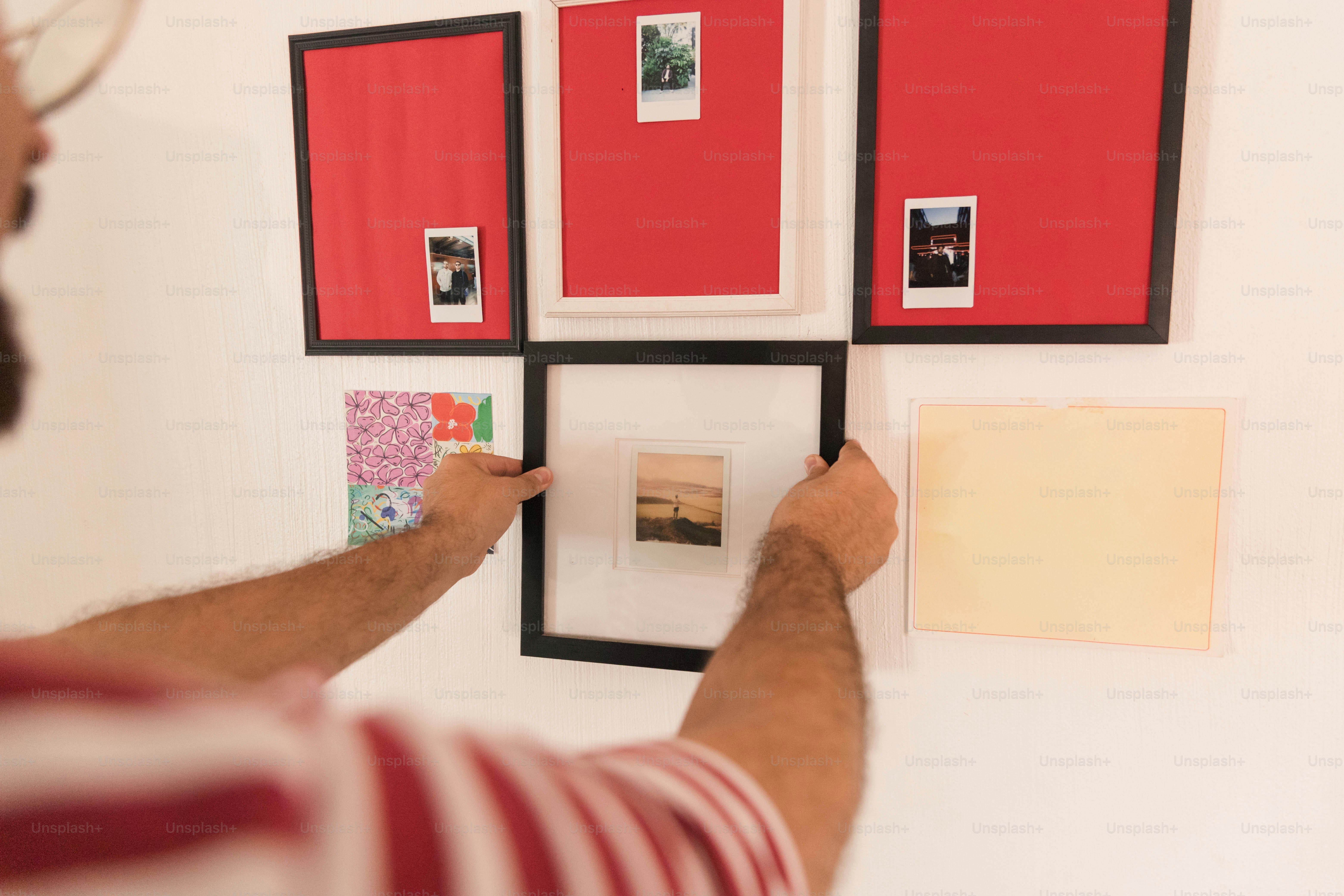 Man hanging picture frame on white wall - Photo on Unsplash+