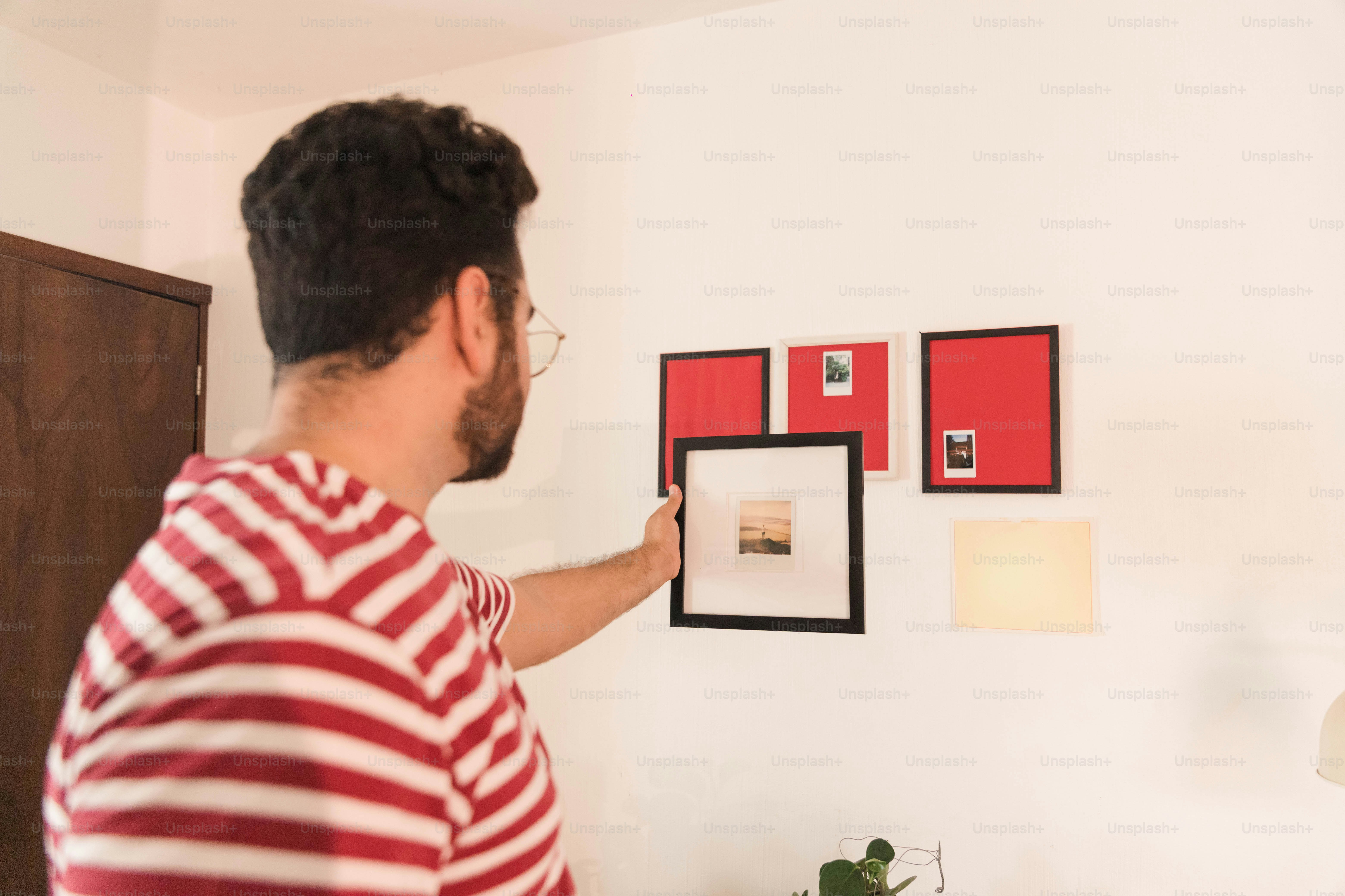 Man hanging picture frame on white wall - Photo on Unsplash+