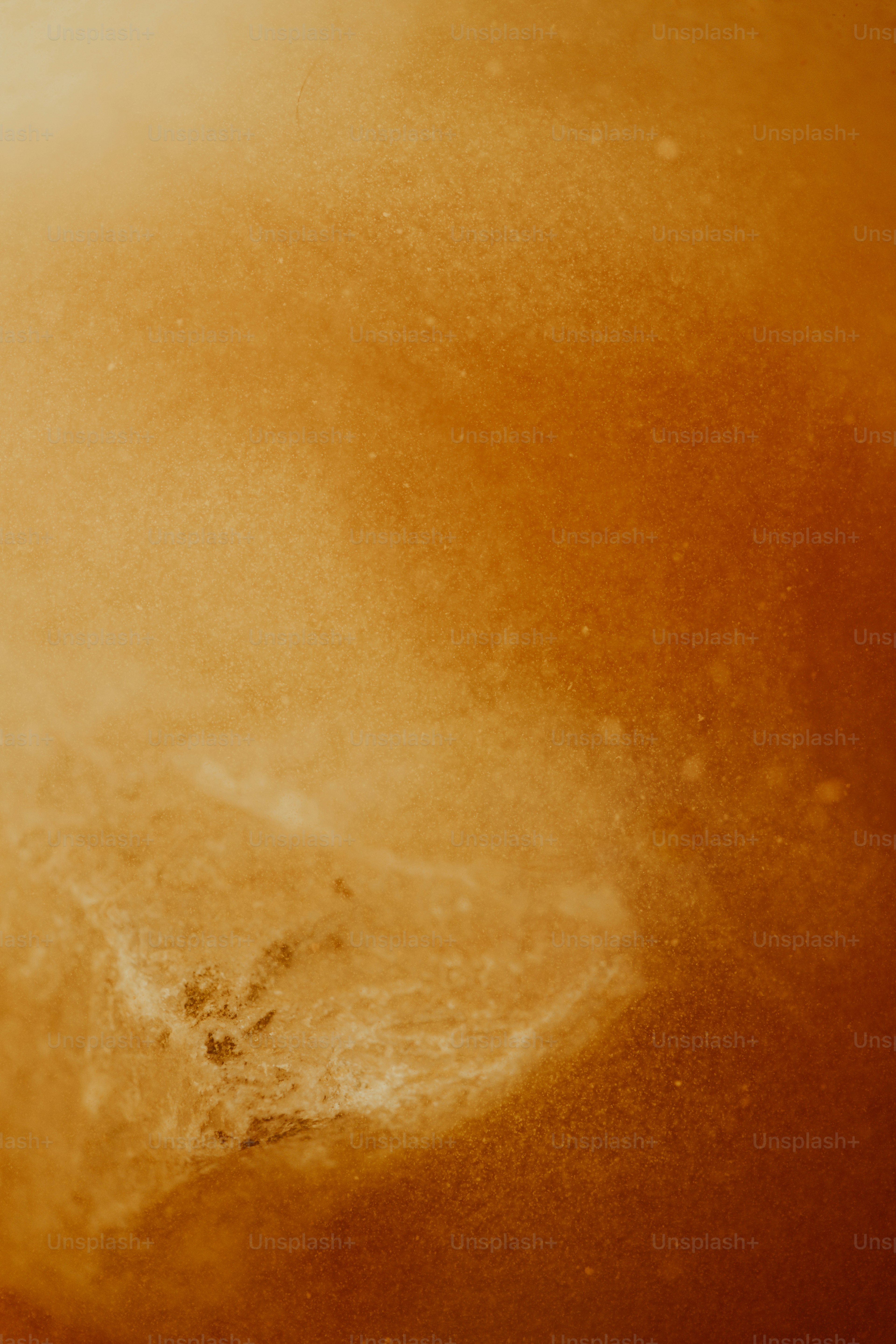 A textured amber surface with a glowing light gradient and fine particles