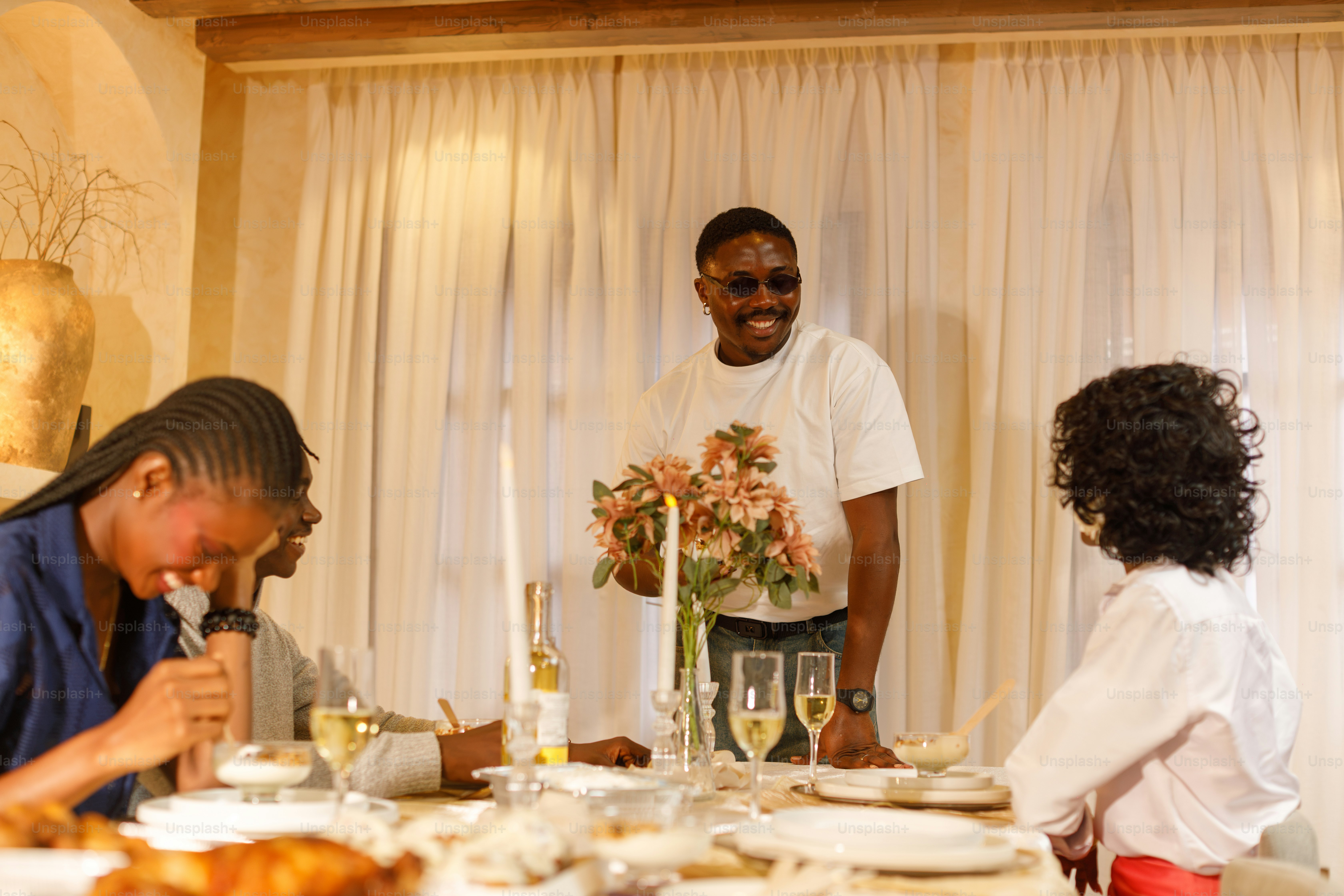 A man in sunglasses smiling at a dinner party with friends in Lagos