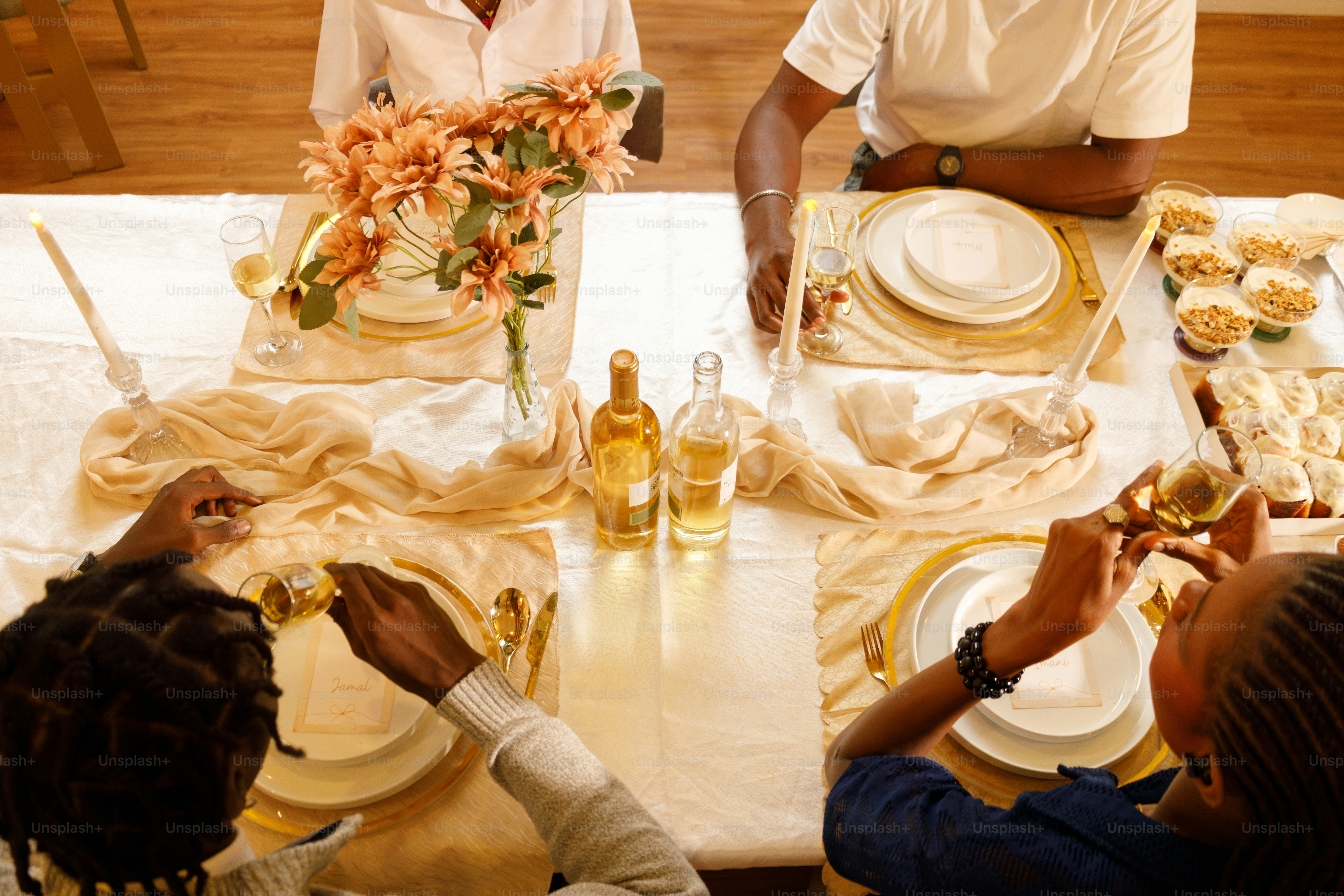 Four people dining at a table with wine, candles, and floral centerpieces