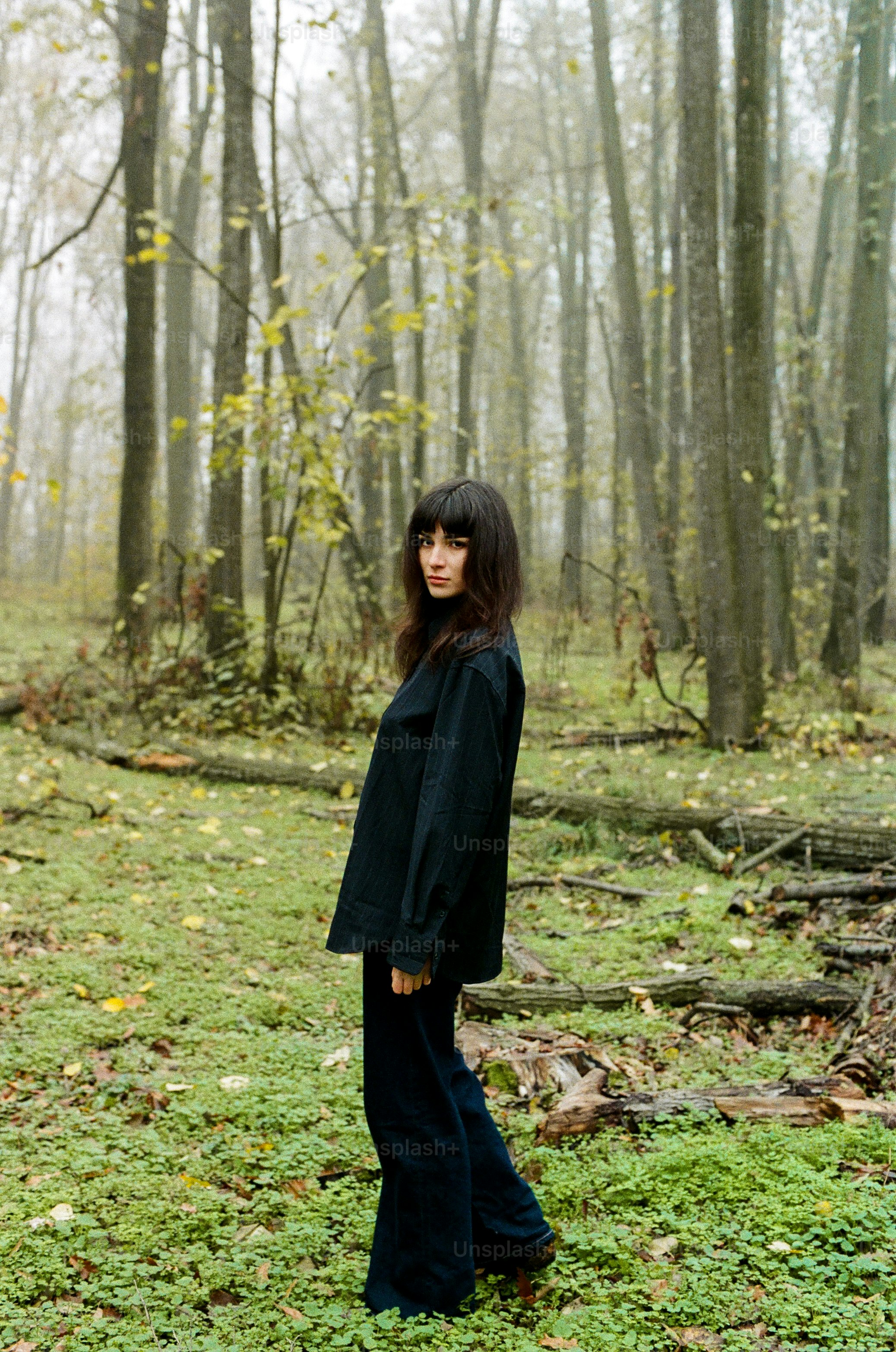 A woman in a black shirt and trousers in a misty autumn forest
