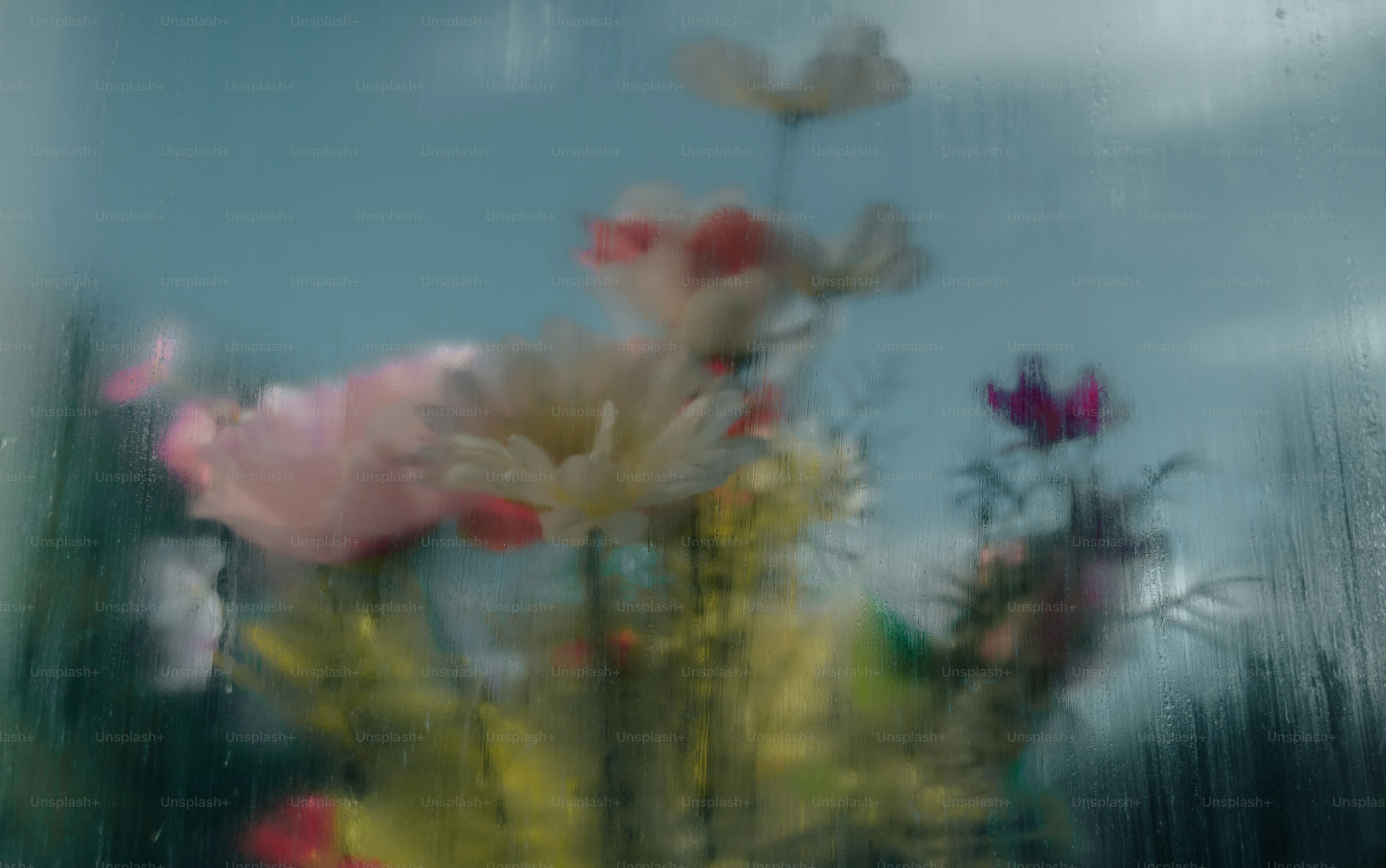 Un mazzo di fiori colorati visti attraverso un vetro della finestra bagnato dalla pioggia