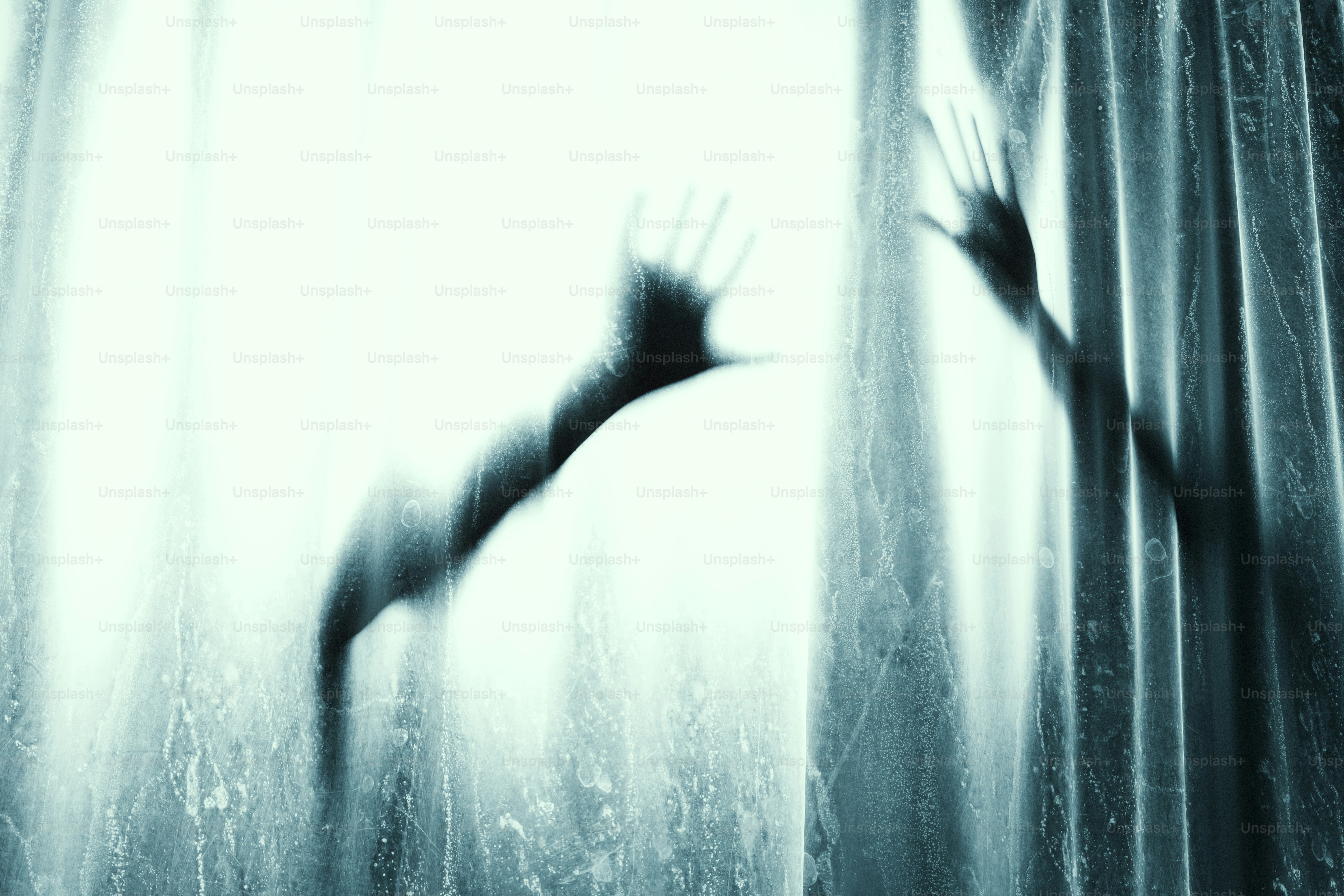 Silhouettes of two hands pressed against a translucent white curtain
