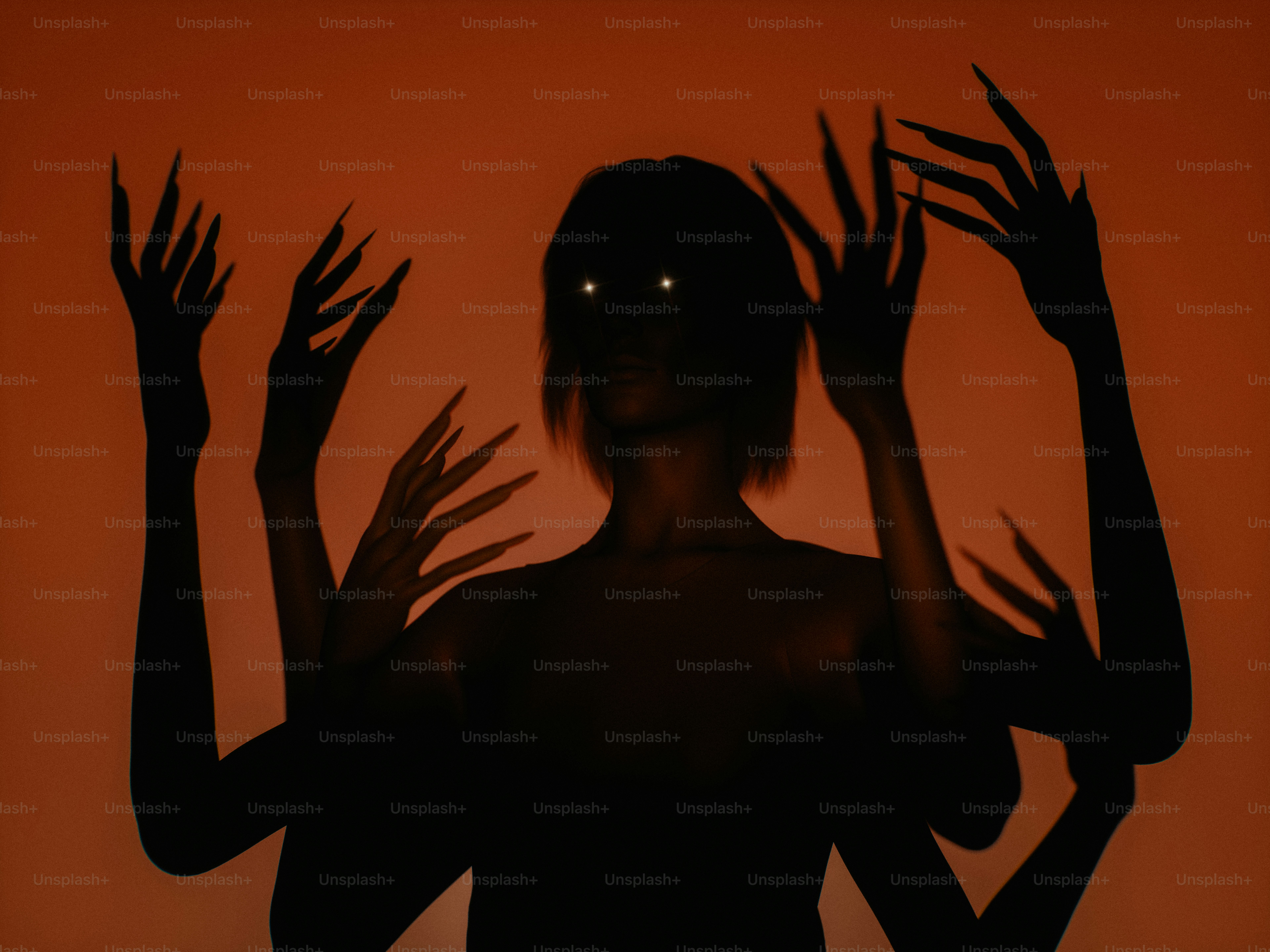 A silhouette of a person with multiple arms against a warm orange background