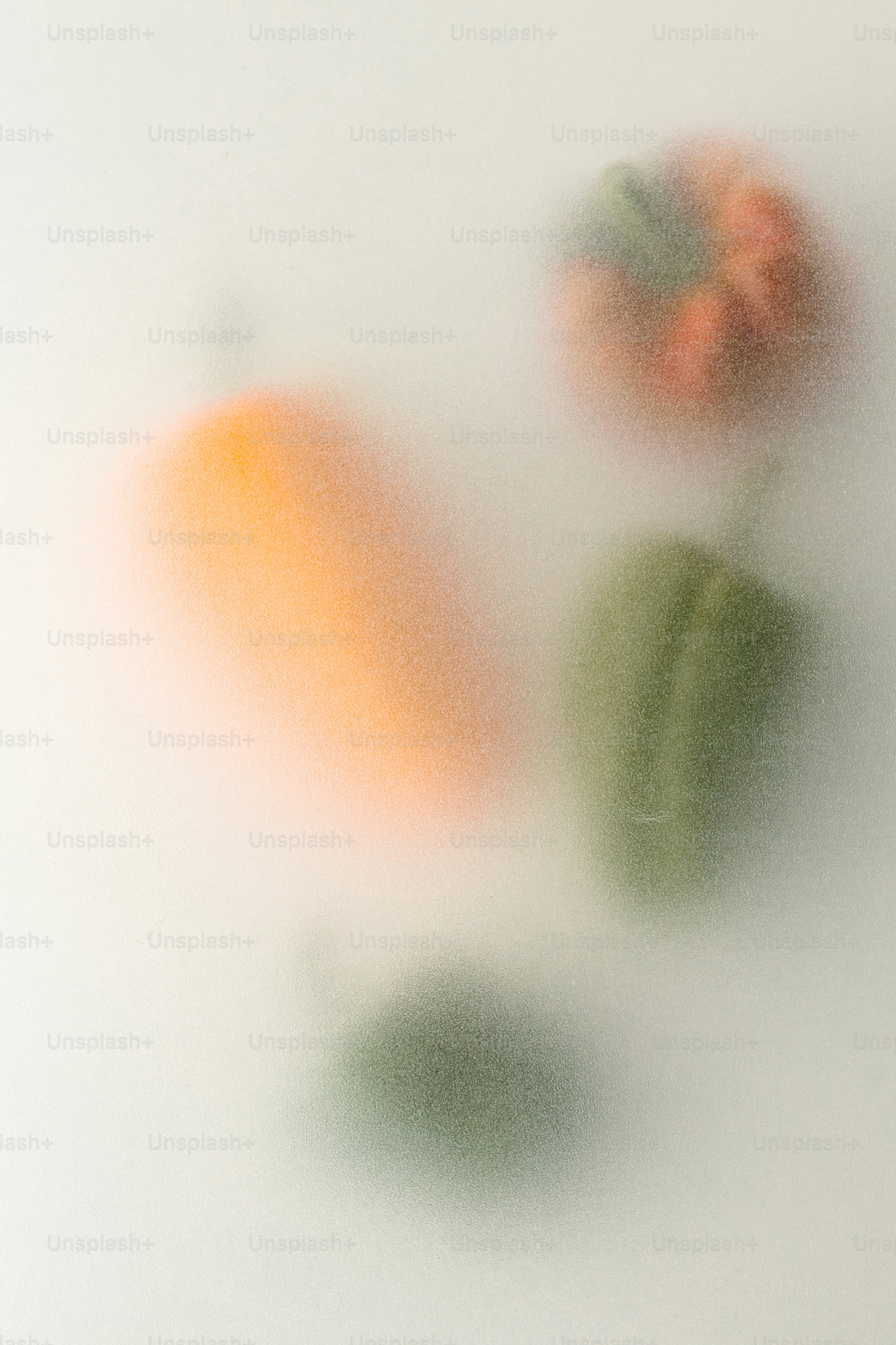 Blurred orange and green bell peppers behind a frosted glass surface