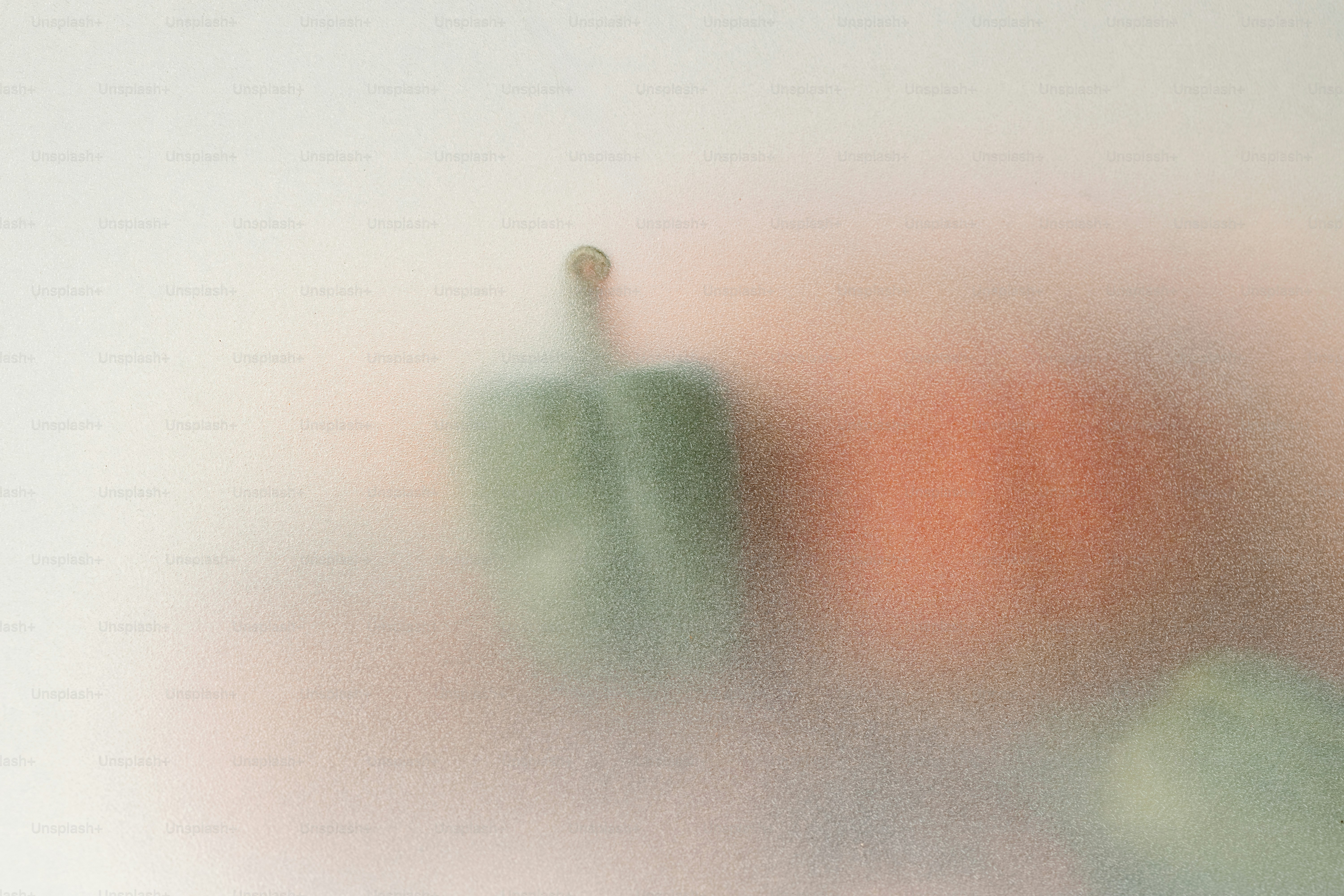 A green bell pepper and a red tomato behind frosted glass