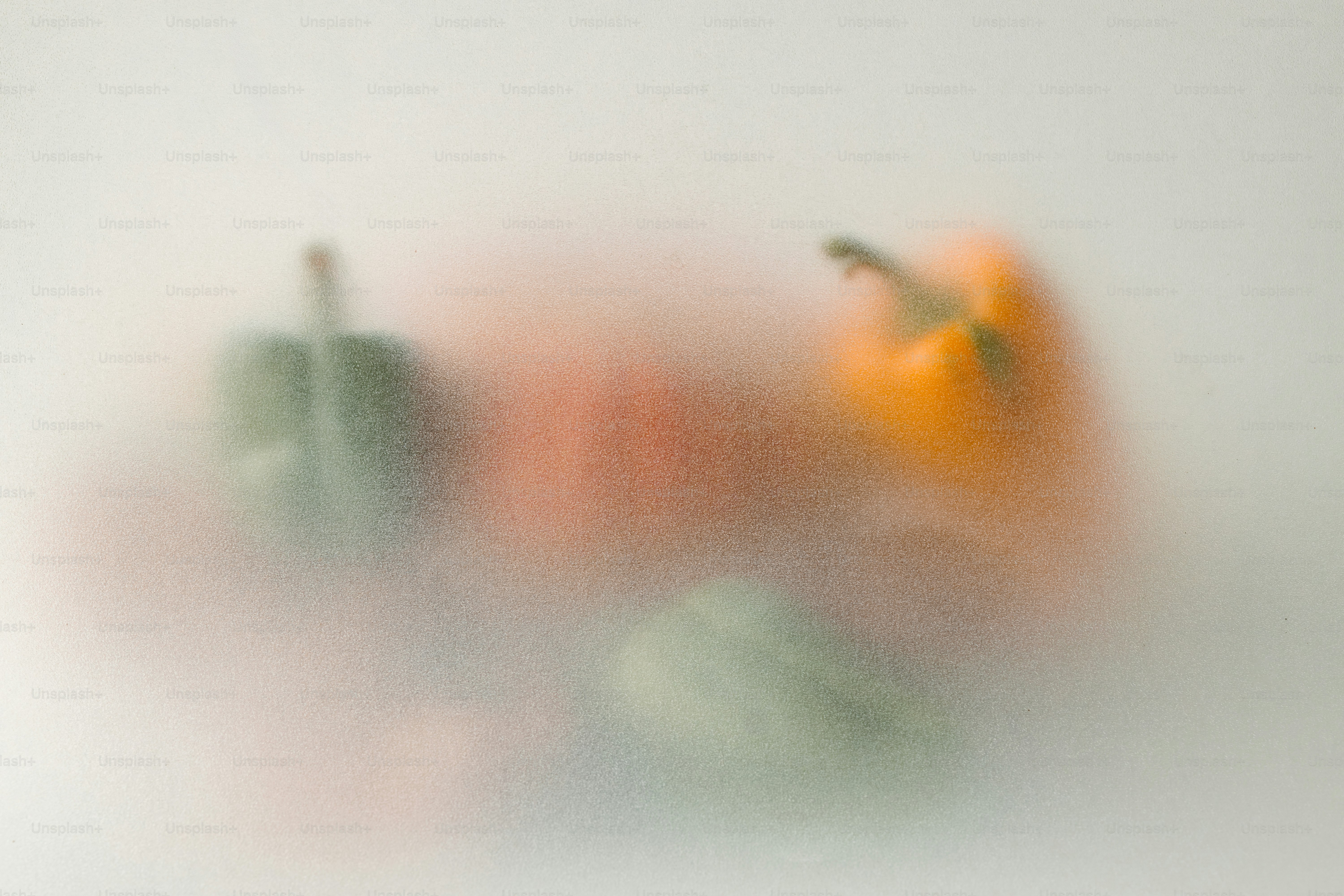 Green and orange bell peppers blurred behind a frosted glass surface