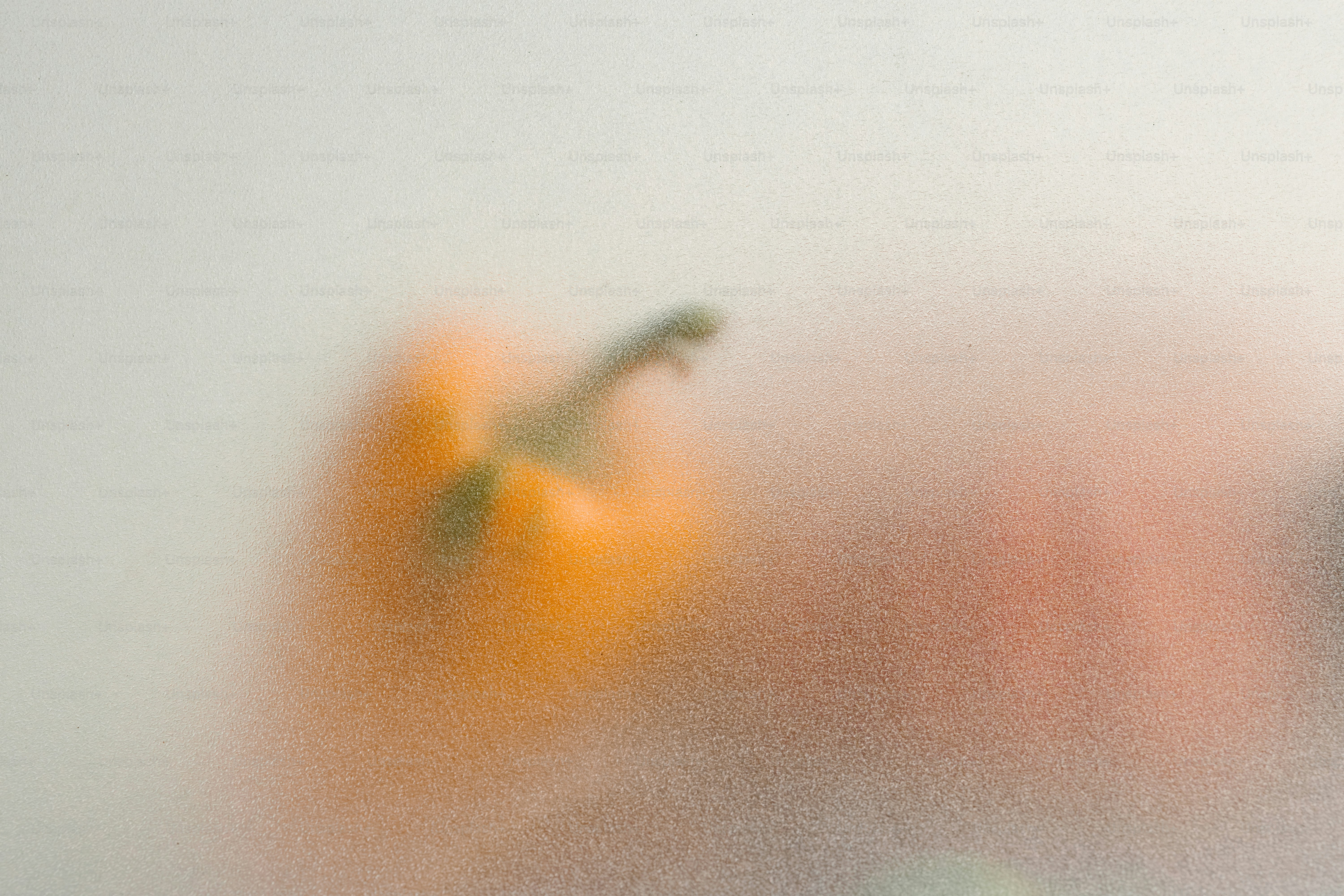A blurred orange bell pepper behind a frosted glass surface