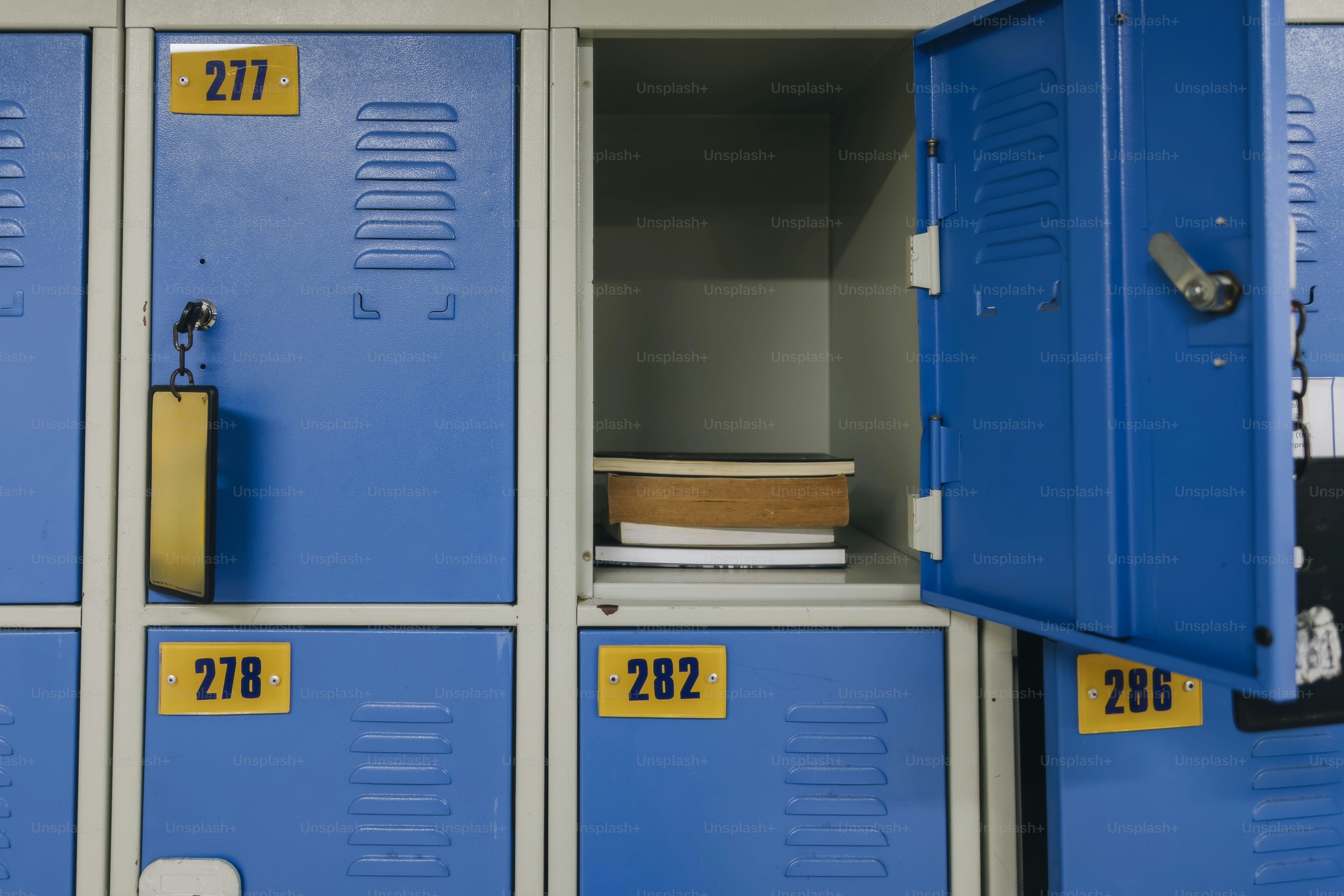Ein Stapel Bücher in einem offenen blauen Metallschließfach mit der Nummer 282