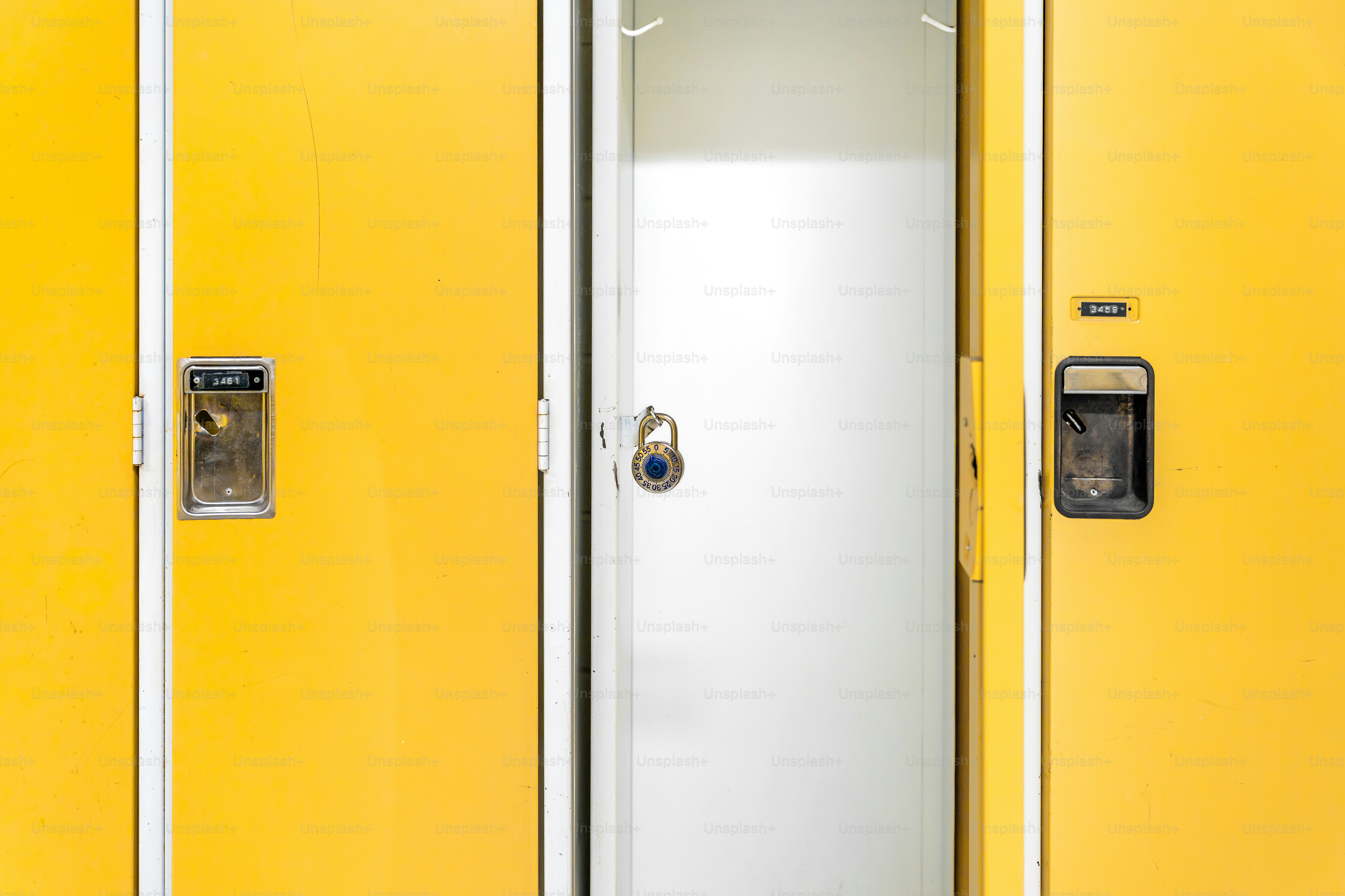 Trois casiers jaunes avec poignées métalliques et un cadenas sur la porte centrale