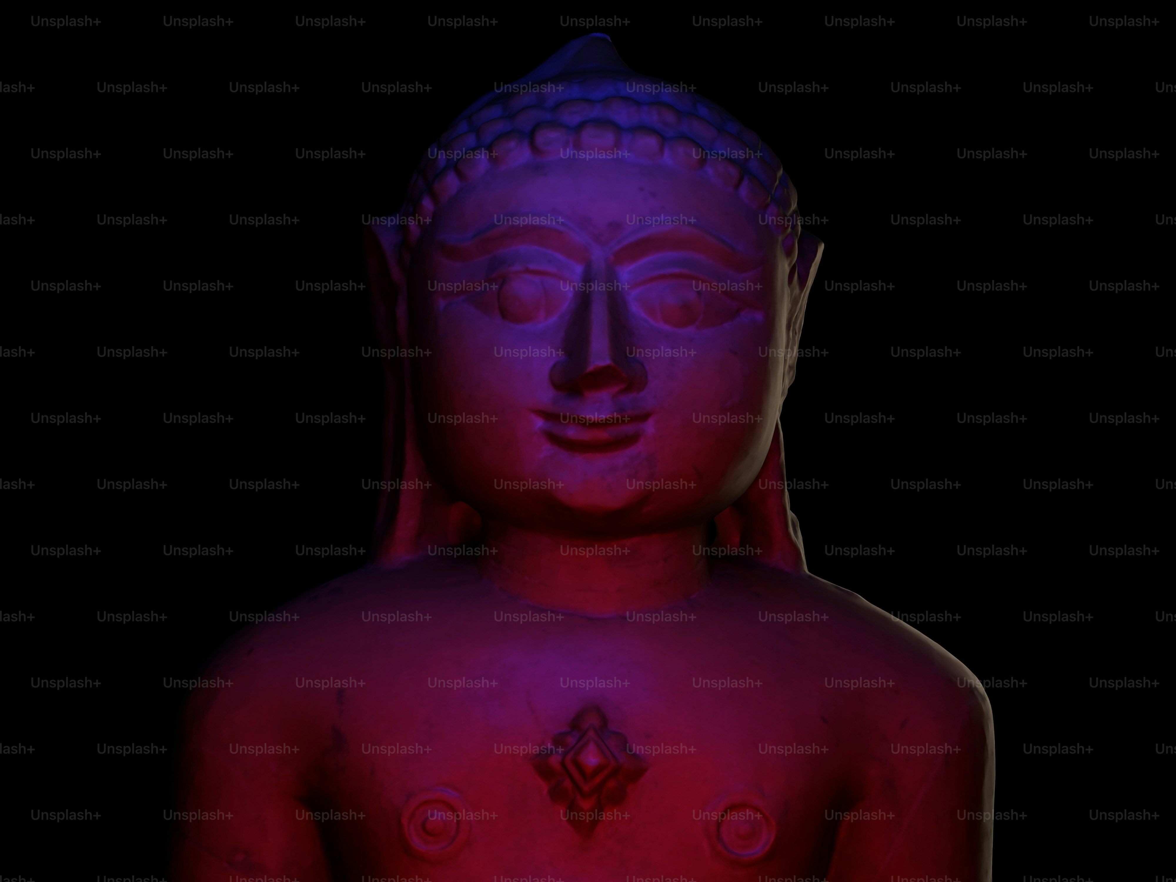 Una estatua de piedra de un Tirthankara iluminada por luces rojas y azules