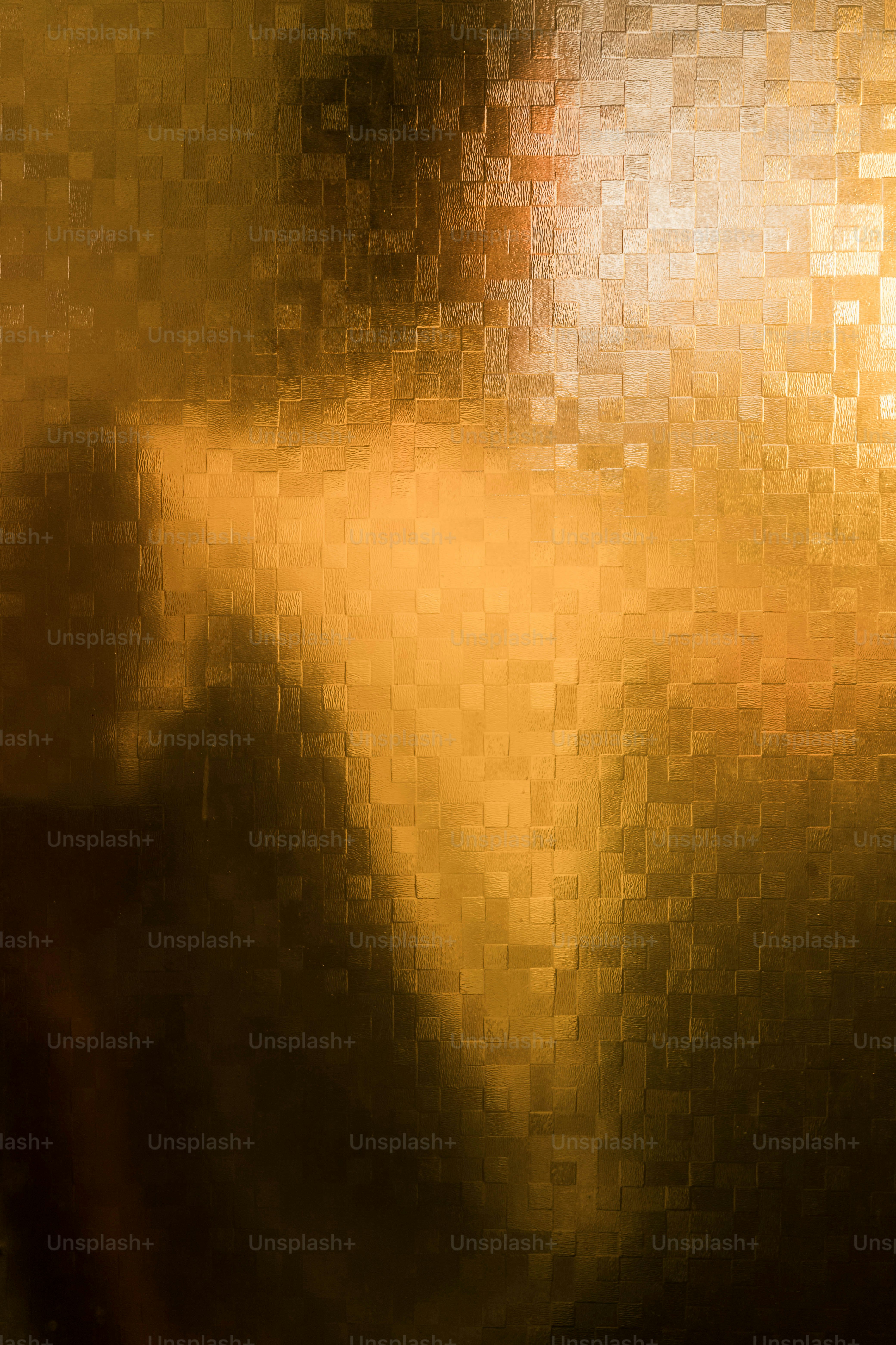 A dark silhouette of a person behind textured golden glass with square patterns